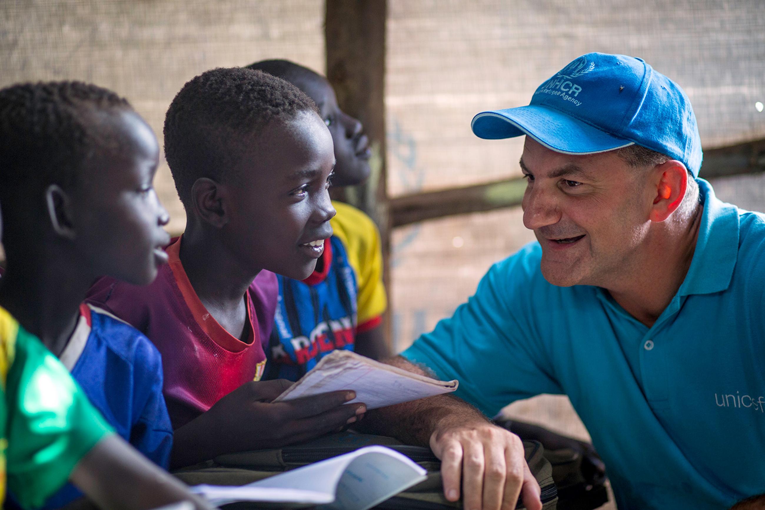 Peter Salama visits a makeshift school at Kule Camp in the Gambella region of Ethiopia on August 12, 2014, when he was the Country Representative of UNICEF Ethiopia. Picture shows Dr. Salama wearing a blue hat talking to several boys in a classroom. They are all smiling. UNICEF/Jiro Ose/UNI170605