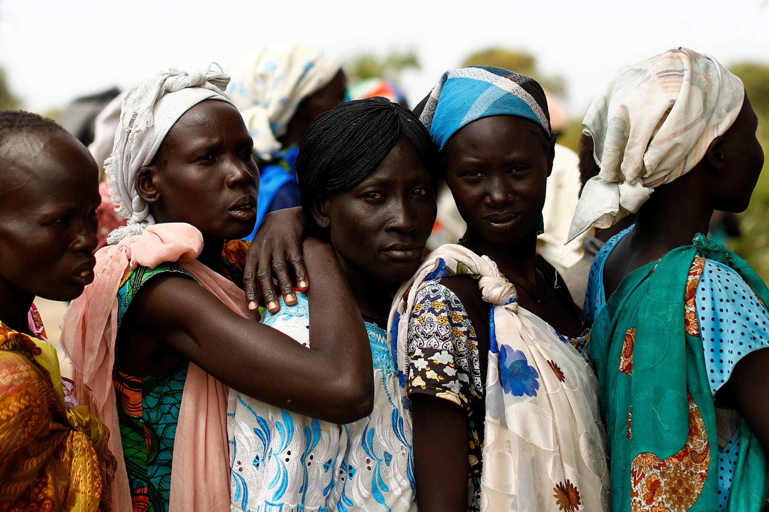 Women wait in line during a UNICEF supported mobile health clinic in the village of Rubkuai in Unity State, South Sudan on February 16, 2017. Picture shows five women in a line with more lined up on the other side of them. The three women in the middle are standing very close, and the third has her arms around the shoulders of the second, suggesting they all know each other. This photo is moving in its simple, straightforward humanity. REUTERS/Siegfried Modola