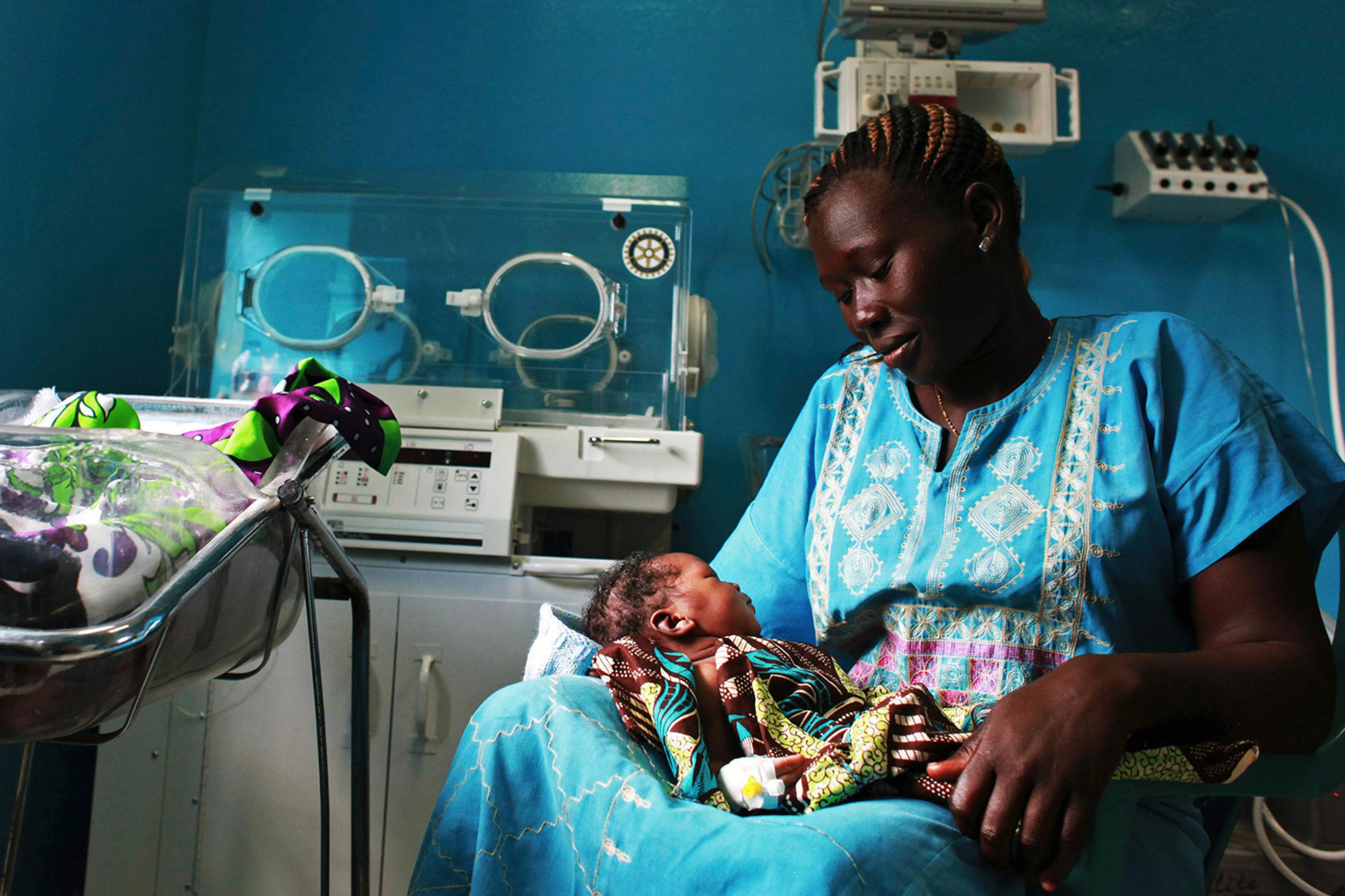 A woman holds her newborn in a nursery at the Juba Teaching Hospital in South Sudan on Apr 3, 2013, which had one of the world's highest maternal mortality rates then at 2,054 per 100,000 live births. Photo shows a woman looking adoringly on her baby, who rests in her lap. REUTERS/Andreea Campeanu