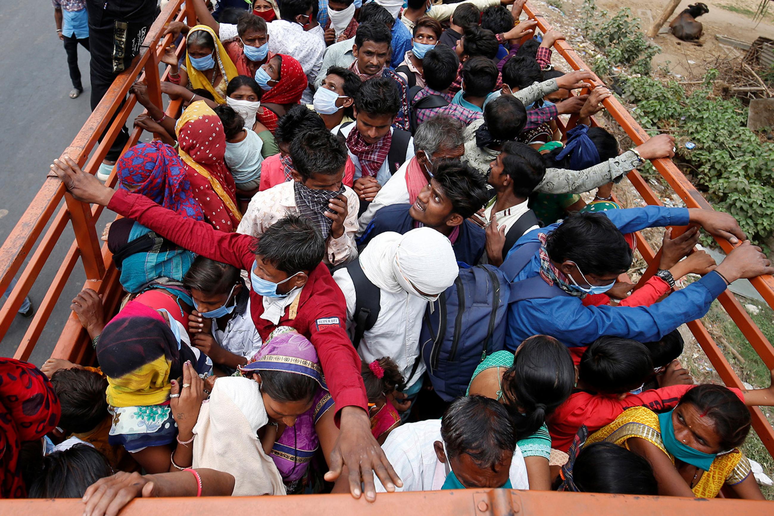 India migrant workers and their families in Ahmedabad board a truck to return to their villages on March 25, 2020 after India ordered a 21-day nationwide lockdown to limit the spread of coronavirus. The photo shows the back of a flatbed truck from above. People are packed in the vehicle beyond capacity, sardined together for what looks like a bumpy ride. REUTERS/Amit Dave