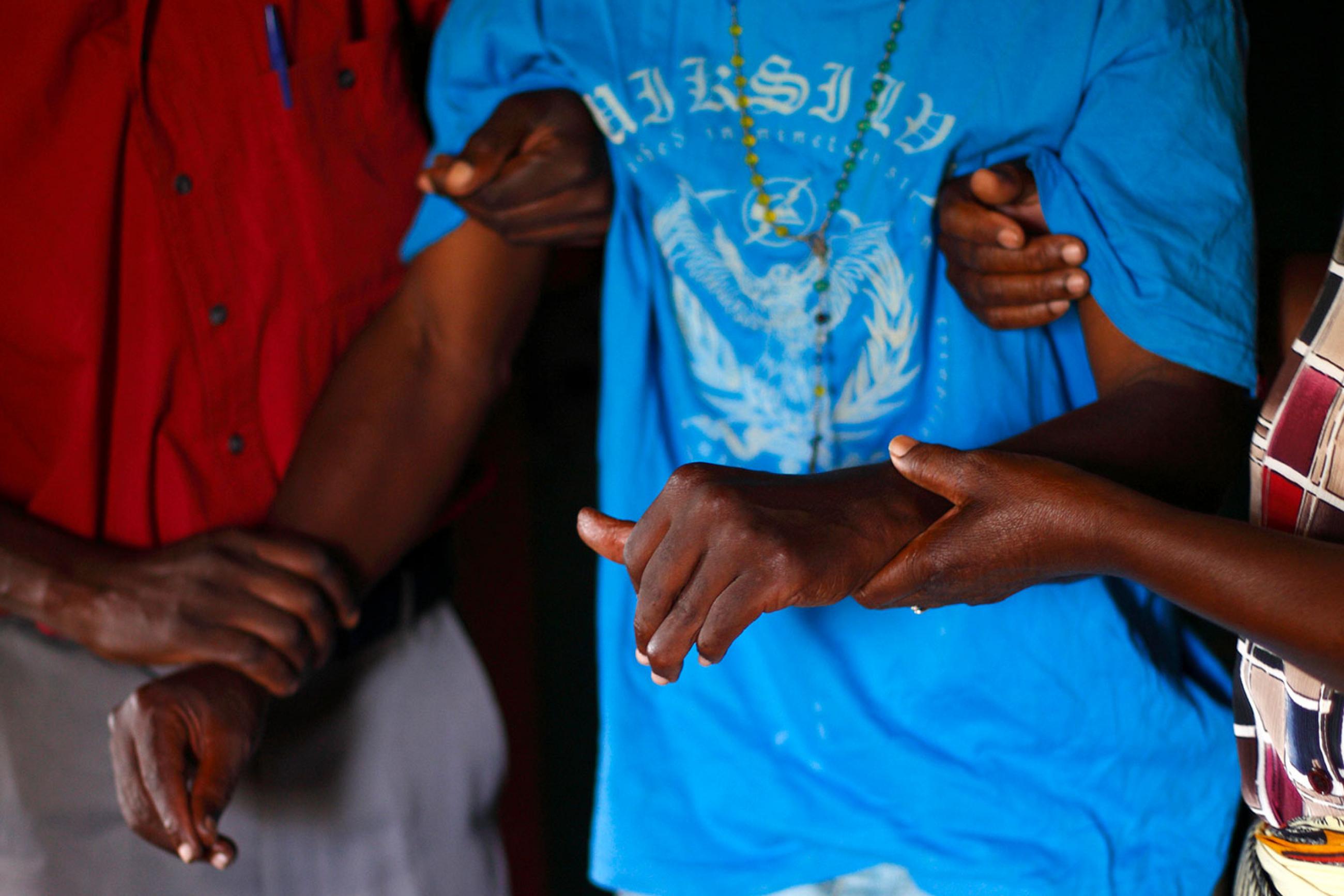 A person with HIV/AIDS is helped to his bedroom by caregivers from a community home-based care team visiting him at his home in Matero township on the outskirts of Lusaka, Zambia on April 17, 2012. The picture shows the torso of a man wearing a loose-fitting light blue shirt being helped by two other people. REUTERS/Darrin Zammit Lupi 