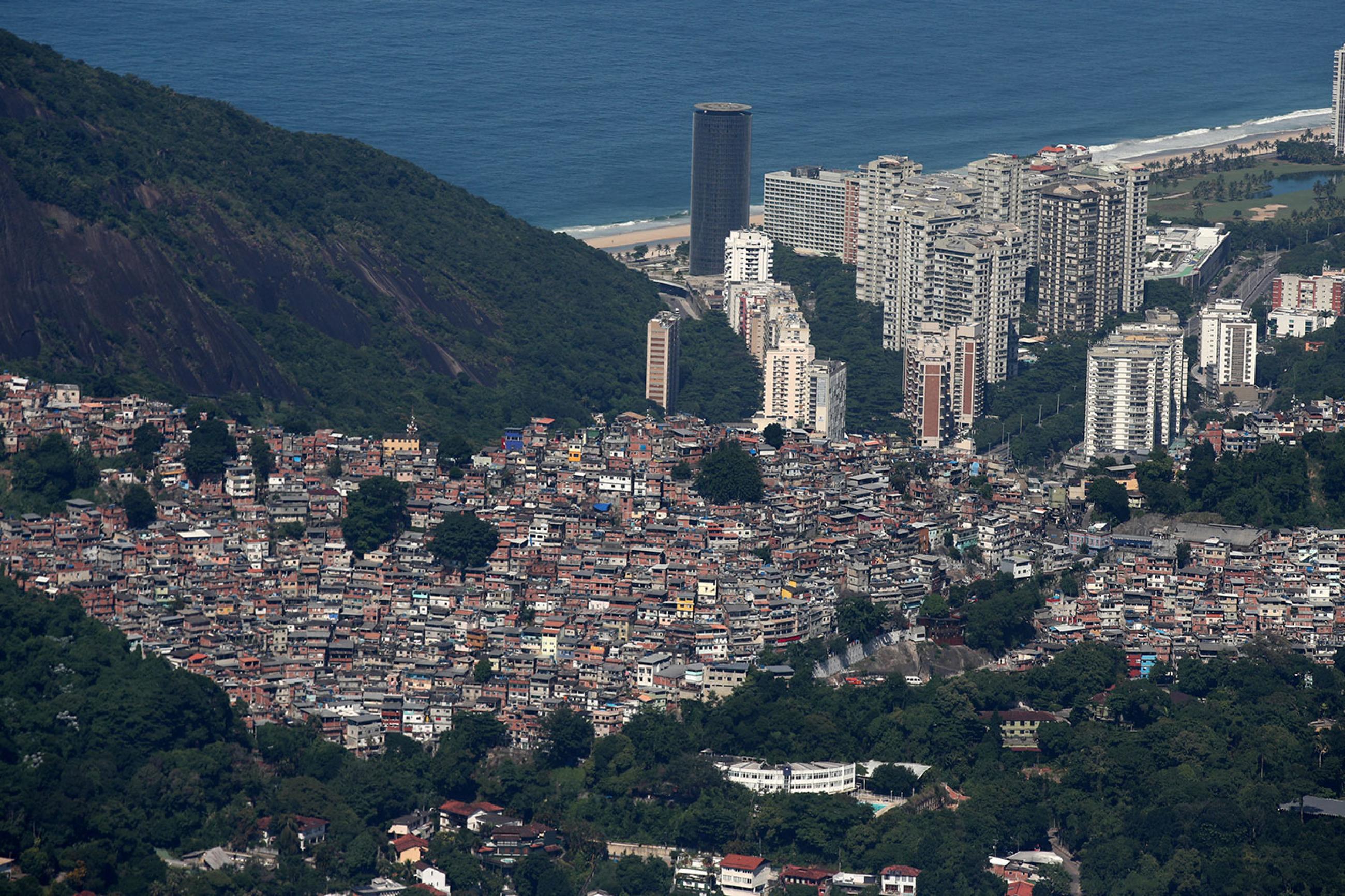 An aerial view of the Rocinha slum in Rio de Janeiro, Brazil on March 26, 2020—during the ongoing crisis over the coronavirus pandemic. The photo is a gorgeous shot taken from the sky showing the slums cascading down the mountain to the coast, which is dotted with modern skyscrapers, and the ocean beyond. REUTERS/Ricardo Moraes