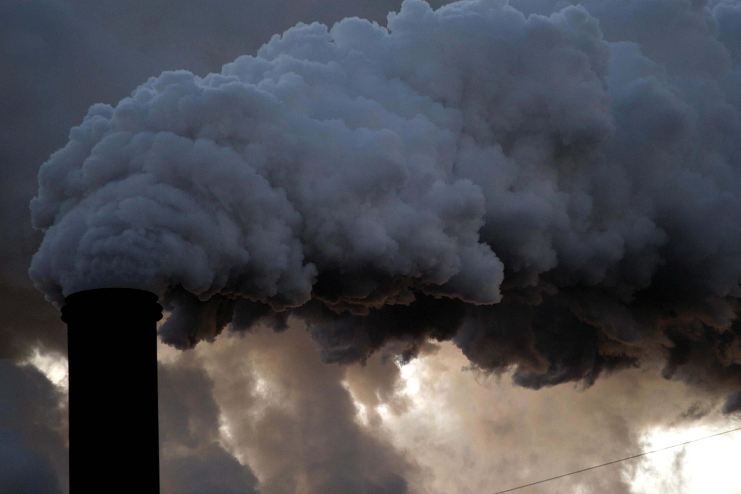 A boiler stack at the Sugar Cane Growers cooperative in Belle Glade, Florida on January 6, 2010. The image shows a large smokestack belching out black billows and blocking the cloudy sky. 