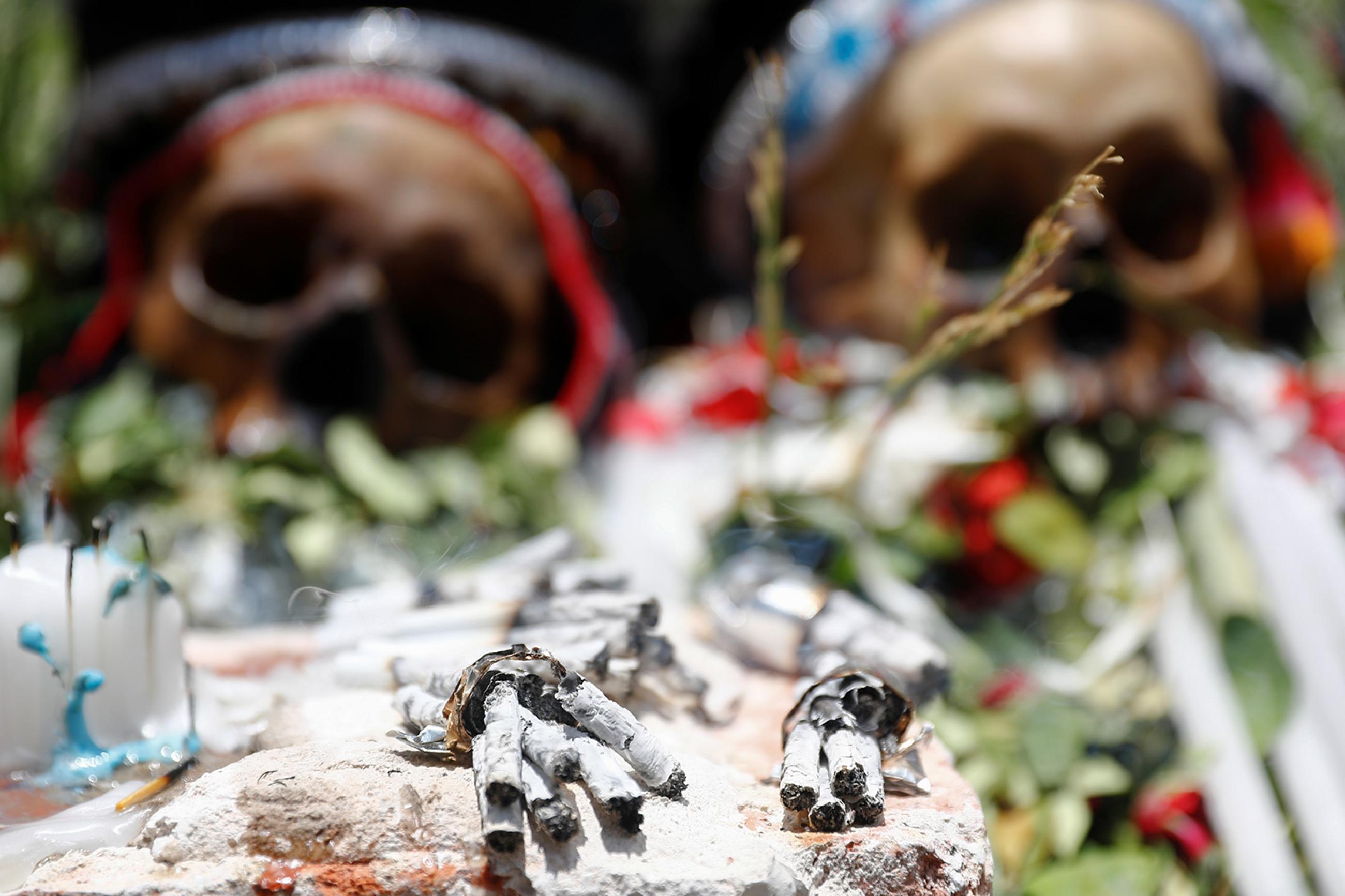 Cigarette butts are seen in front of exhibited skulls during the Day of Skulls celebrations in La Paz, Bolivia November 8, 2019. The photo shows two human skulls laid out with flowers in a ceremonial way with a number of burned cigarettes in the foreground. REUTERS/Kai Pfaffenbach