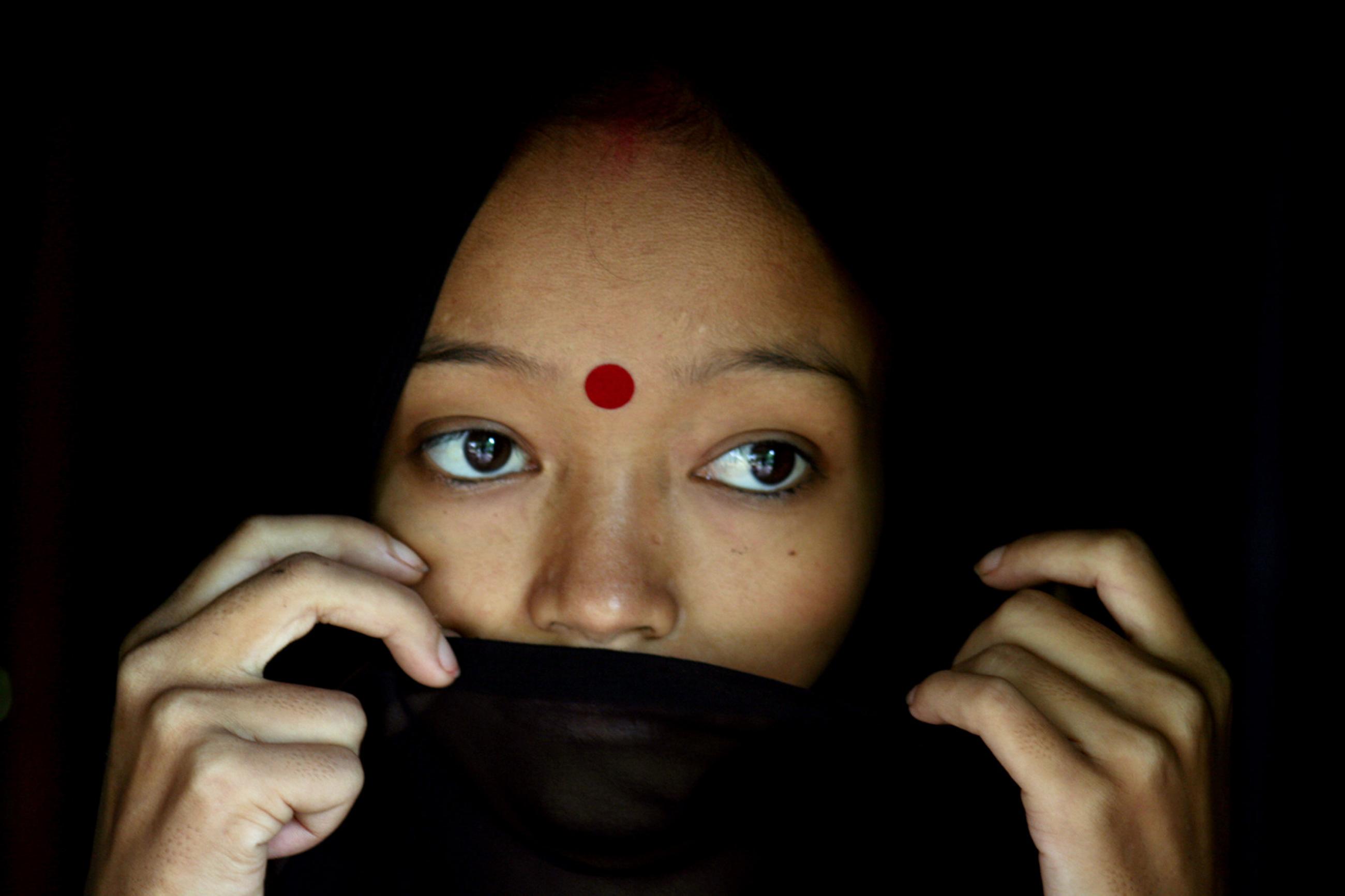 A woman living with HIV/AIDS stands in her hut in the northeastern Indian city of Siliguri on July 23, 2005. The photo shows the woman with a wrap covering her mouth. REUTERS/Rupak De Chowdhuri