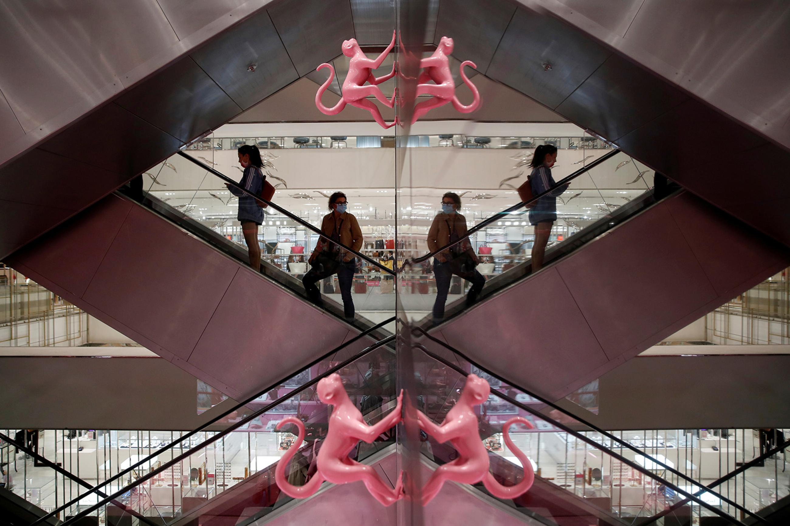 Customers wearing facemasks are reflected in a mirror as they stand on an escalator inside the department store Le Printemps Haussmann in Paris, France, amid the coronavirus pandemic on May 28, 2020. The photo shows people on an escalator with the photo showing mirror images on the left and right of the frame. REUTERS/Gonzalo Fuentes
