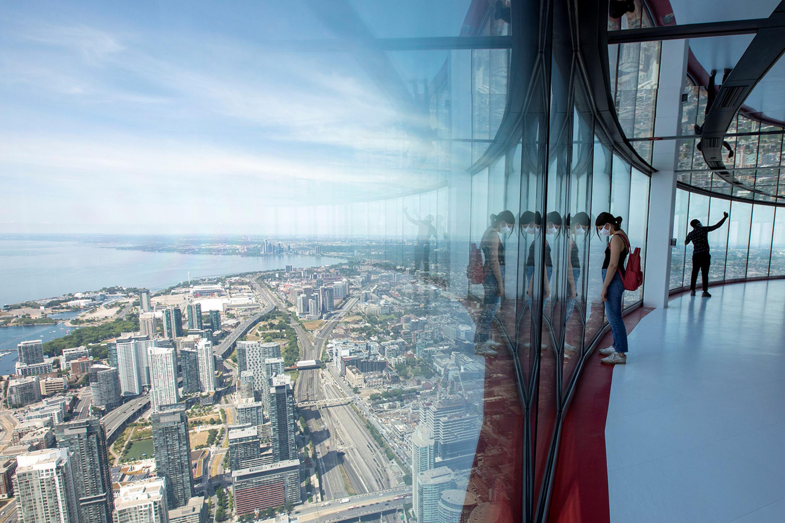 Bird's eye view: visitors take in a panoramic scene of the city of Toronto, Canada, from the 553 meters (1815 feet) high CN Tower, which just reopened after coronavirus restrictions on July 15, 2020. The photo shows a woman wearing a mask looking out from the skyview of the tall building with the Toronto cityscape beneath her. REUTERS/Carlos Osorio