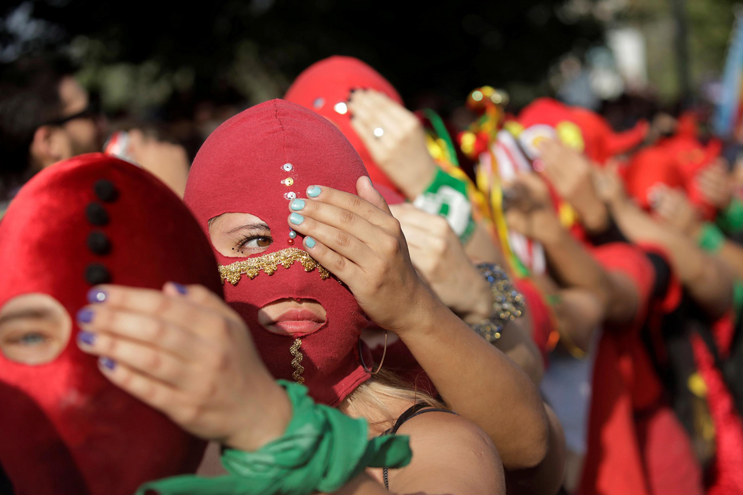 "We cannot afford to unsee domestic abuse after COVID-19," the authors write. Here women wearing masks take part in a protest against gender violence in Santiago, Chile, on December 6, 2019. The photo is a striking image of women wearing red masks lined up, each person holding a hand over one eye of the person in front of them. REUTERS/Andres Martinez Casares