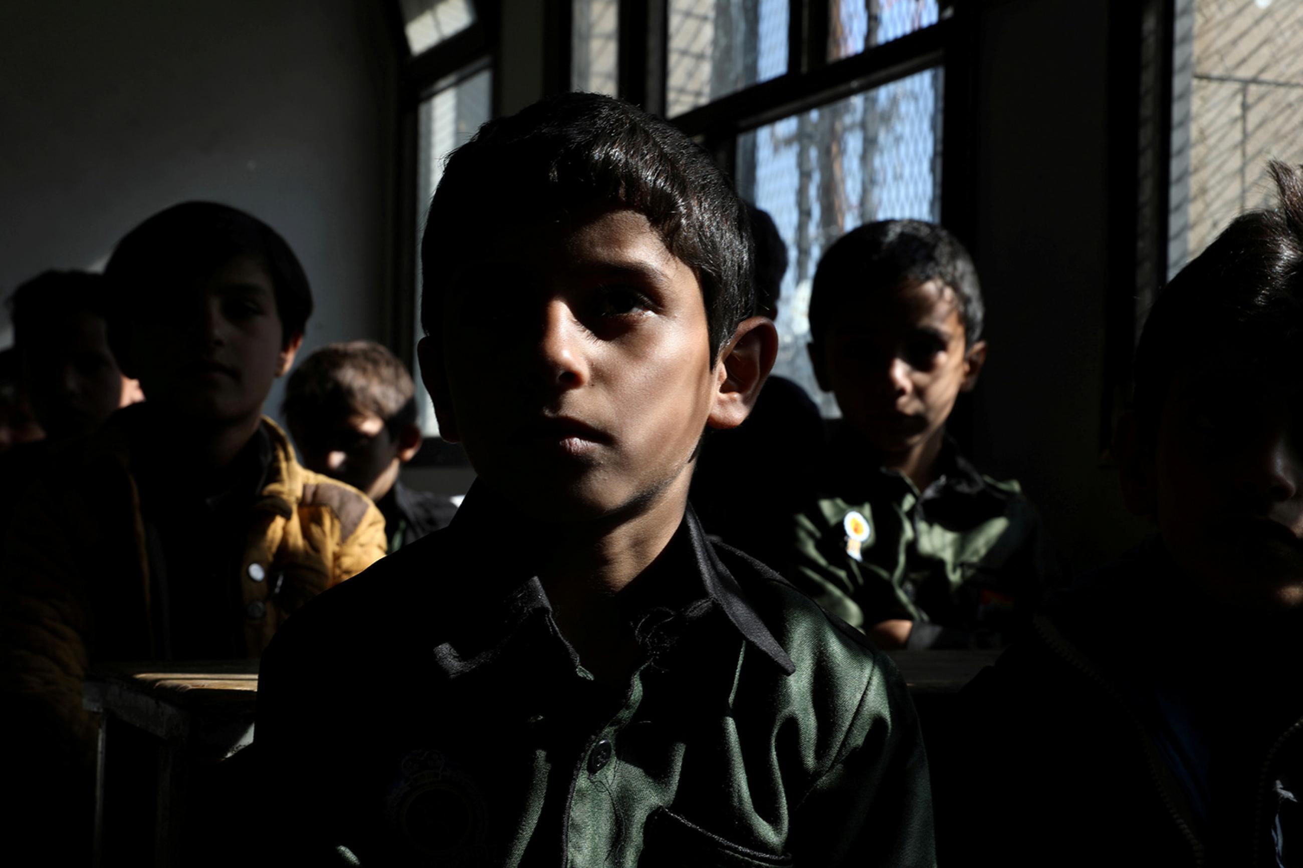 Students attend a class at the beginning of the school year amid fears of the spread of the coronavirus disease (Covid-19) in Sanaa, Yemen October 18, 2020. The photo shows a darkened classroom with several students facing the camera. REUTERS/Khaled Abdullah