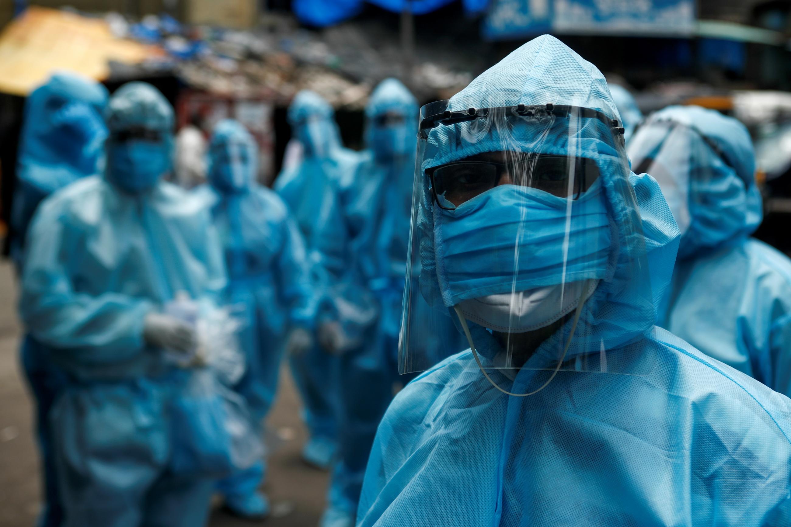 Health-care workers wait to take off their personal protective equipment after the end of a check-up camp for the COVID-19) at a slum in Mumbai, India on June 14, 2020.