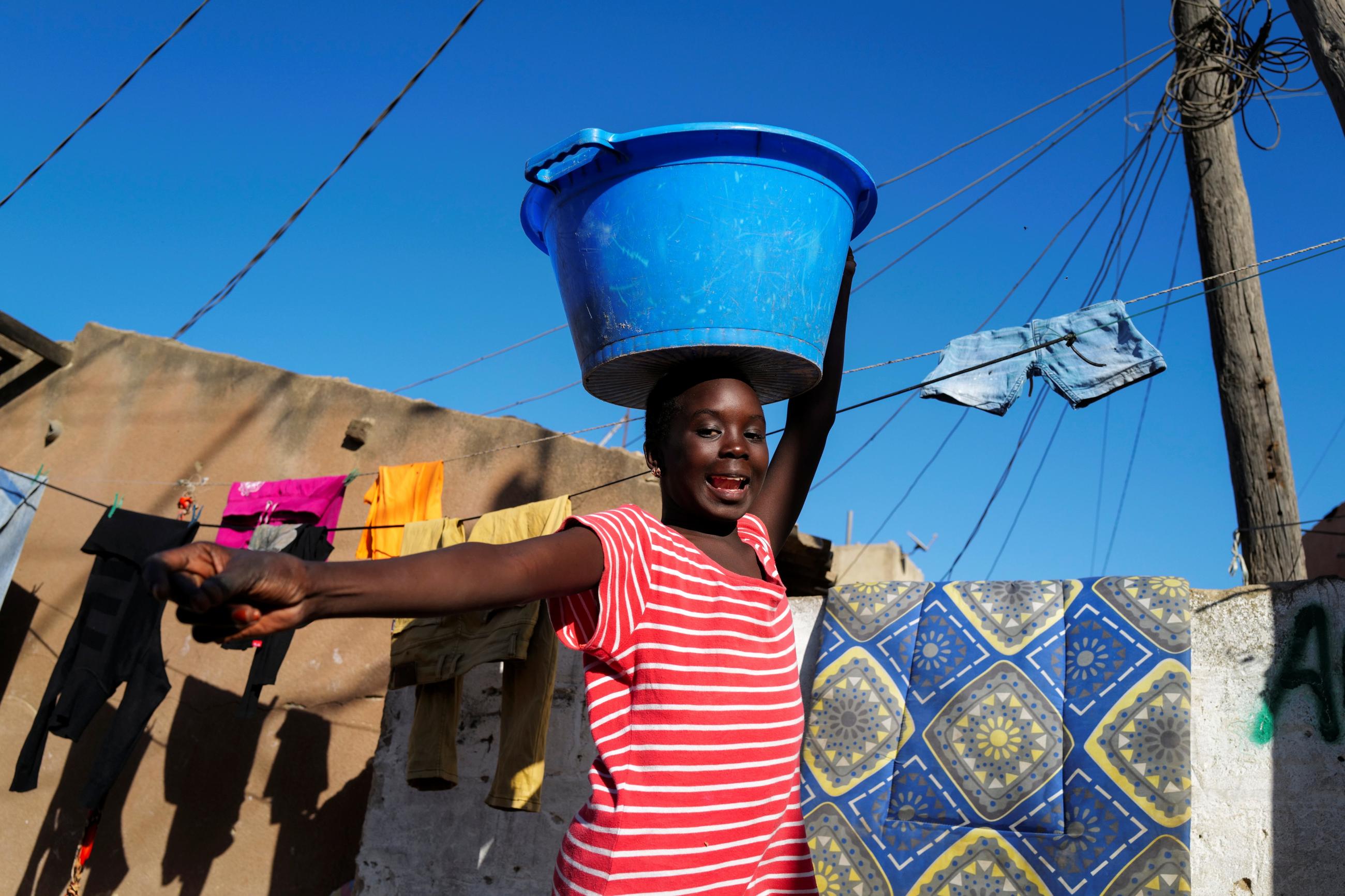 A girl carries a bucket with laundry on her head while heading home as the spread of the coronavirus disease continues, in Yoff neighbourhood, Dakar, Senegal on January 26, 2021.