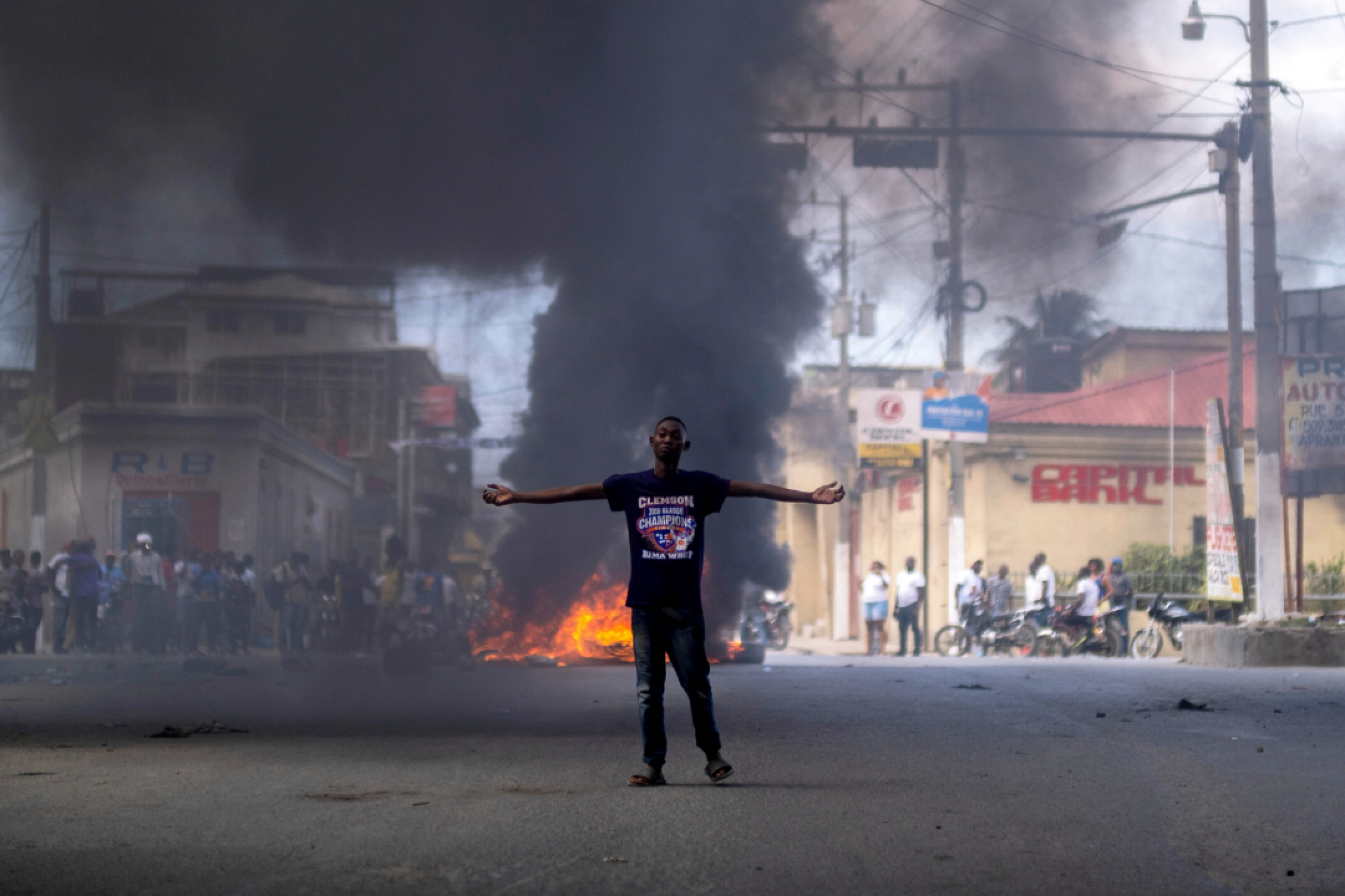 A man stands in front of a burning barricade during a protest against the assassination of Haitian President Jovenel Moise in Cap-Haitien, Haiti on July 22, 2021.