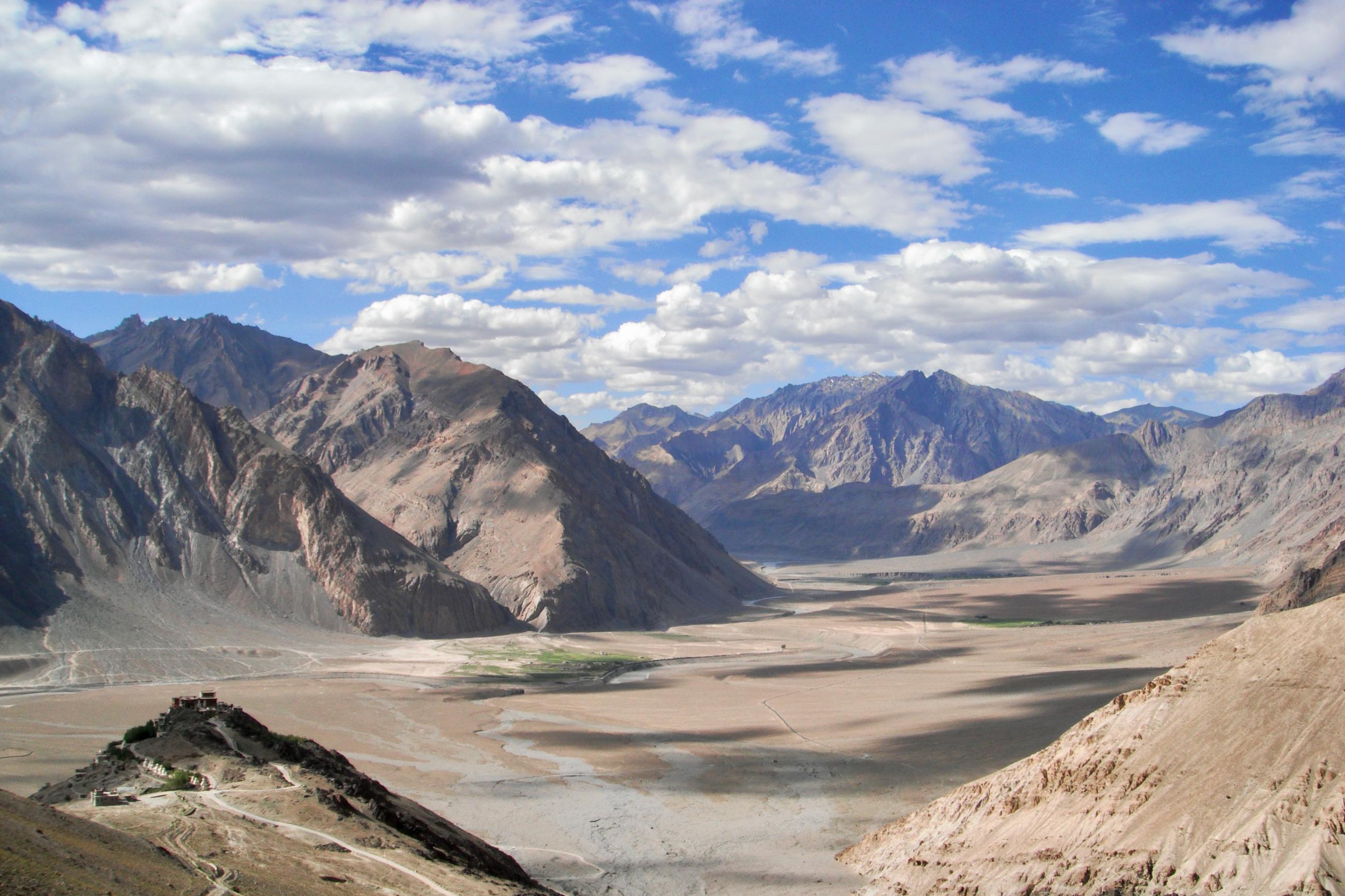 White clouds in a bright blue sky above the Himalaya Mountains and Zanskar Valley