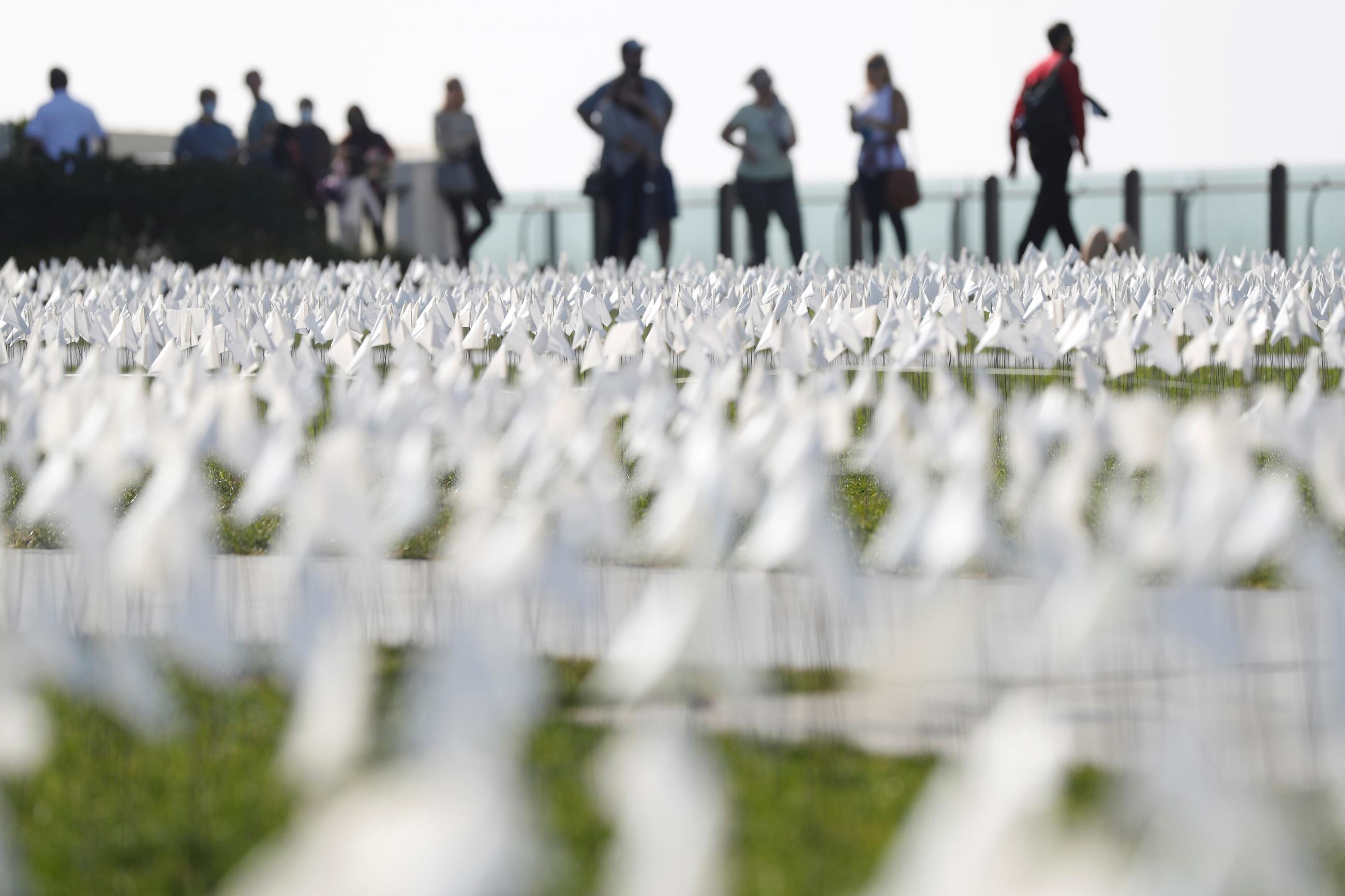People wander through a COVID memorial made of 26,661 white flags at the Griffith Observatory in Los Angeles, California, on November 20, 2021. 