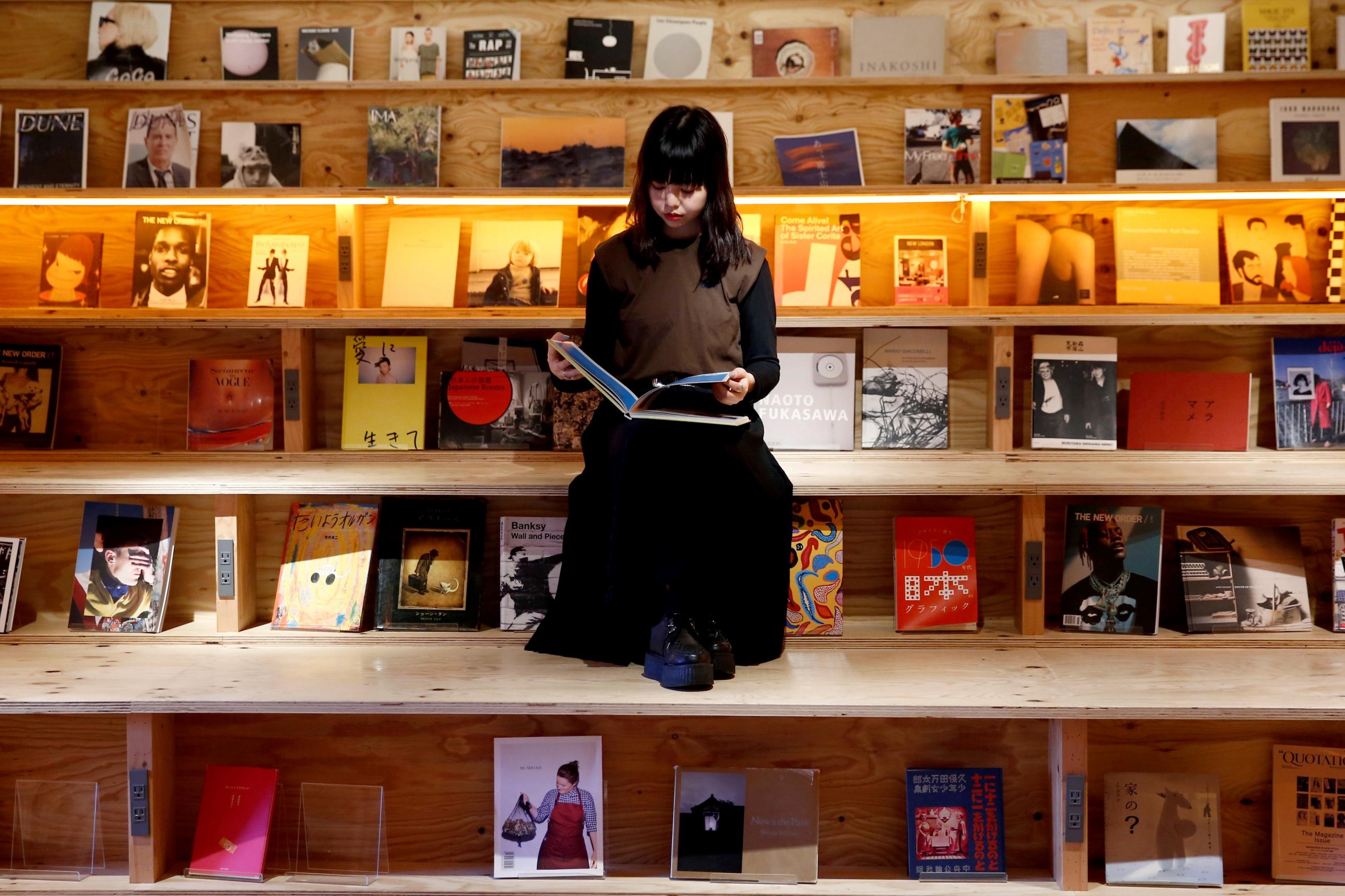 A woman reads a book at the Shinjuku branch of Book and Bed, an accommodation combined with book cafe where guests can sleep in hidden bunks built into a large bookshelf, during a photo opportunity in Tokyo, Japan September 14, 2018.