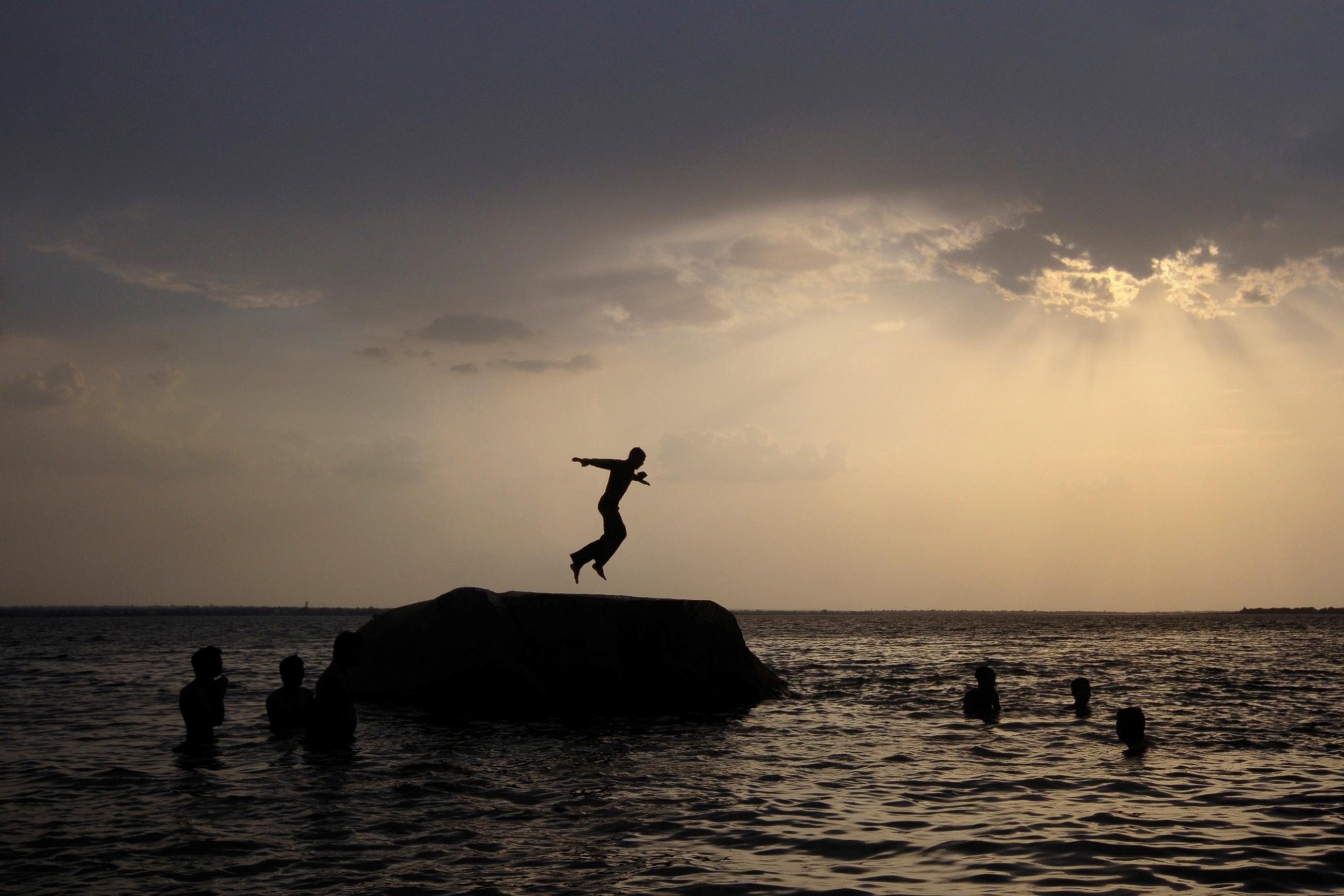 As the sun sets, a boy prepares to jump off a rock into the waters of the Osman Sagar Lake near the southern Indian city of Hyderabad May 29, 2011. 