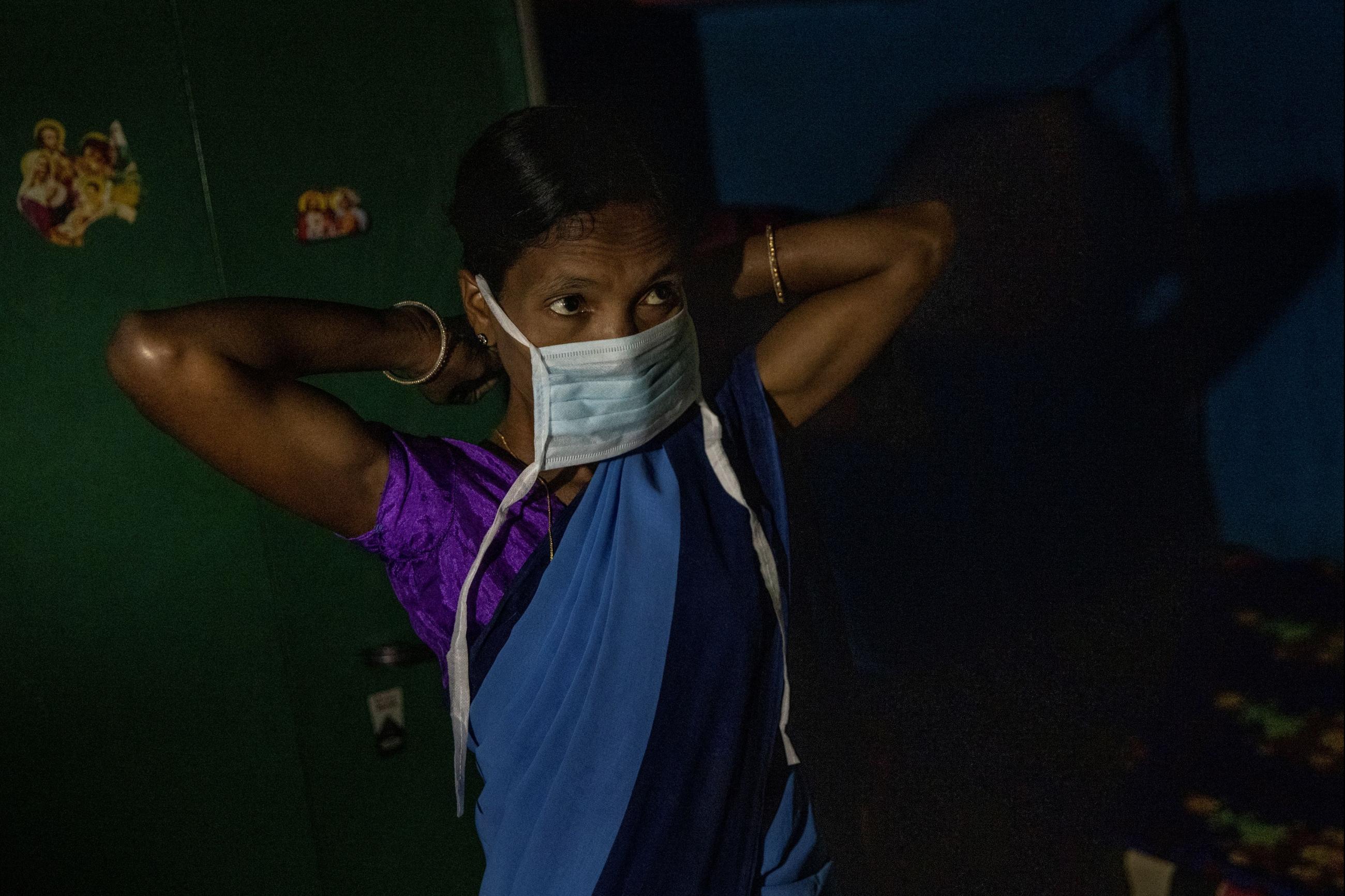  a health worker, puts on a protective face mask as she gets ready to travel