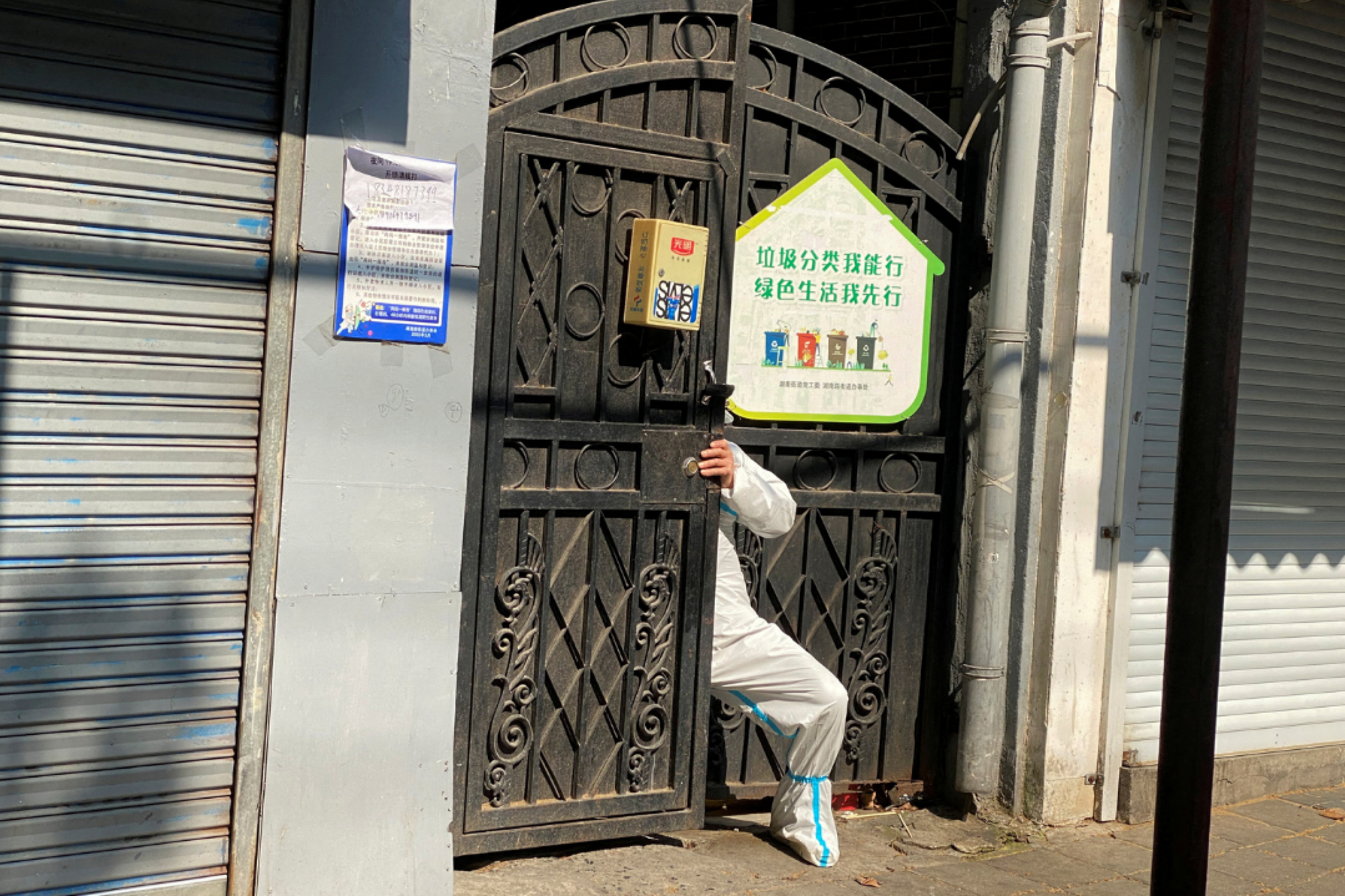 A person in a protective suit squeezes through a locked gate of a residential compound, during a COVID-19 outbreak and lockdown in Shanghai, China, on April 21, 2022. 