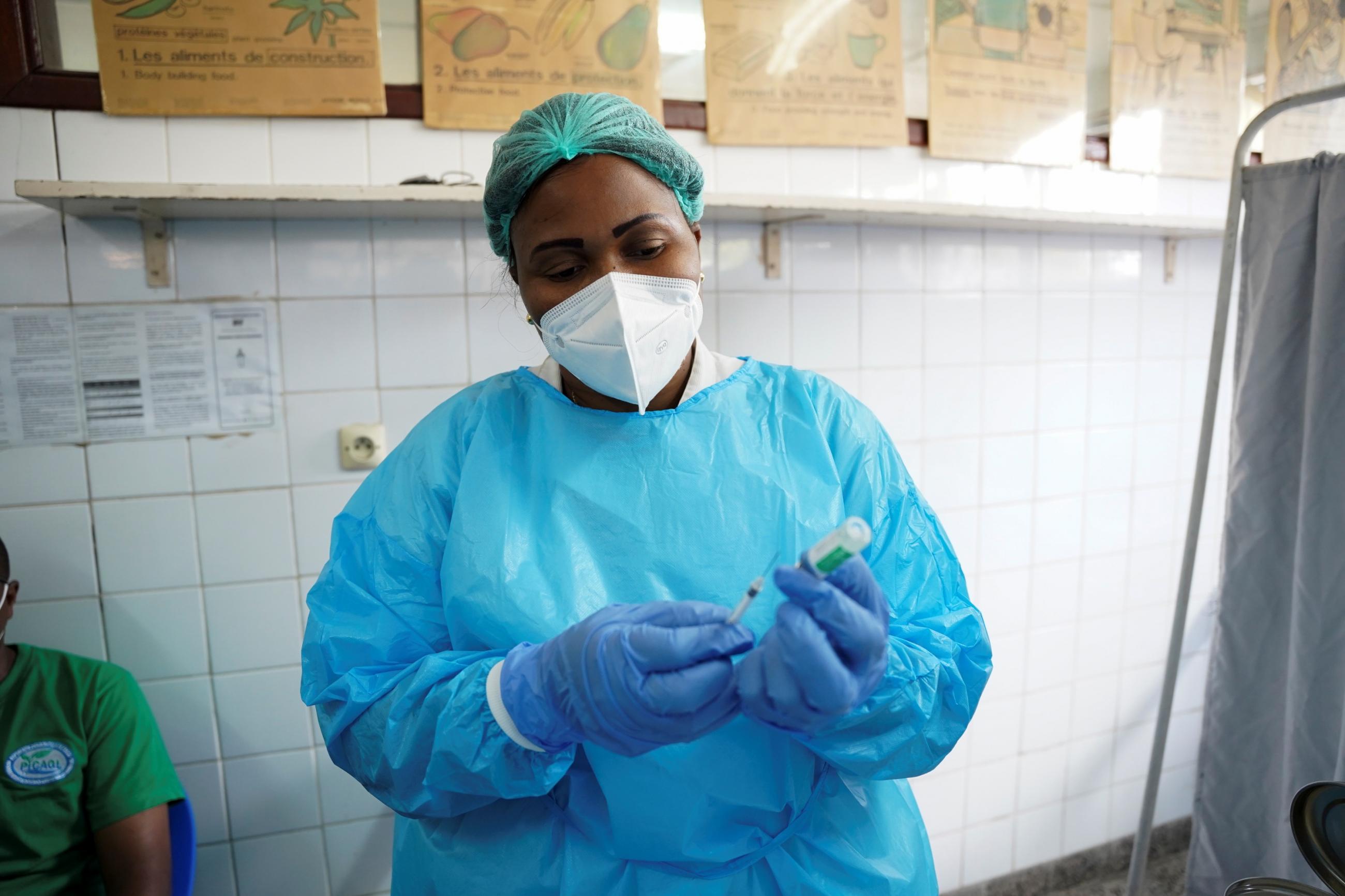 A nurse in a blue protective suit, white mask, and green hair net prepares a COVID-19 vaccine at the Ngaliema Clinic in Kinshasa, Democratic Republic of Congo, April 29, 2021.