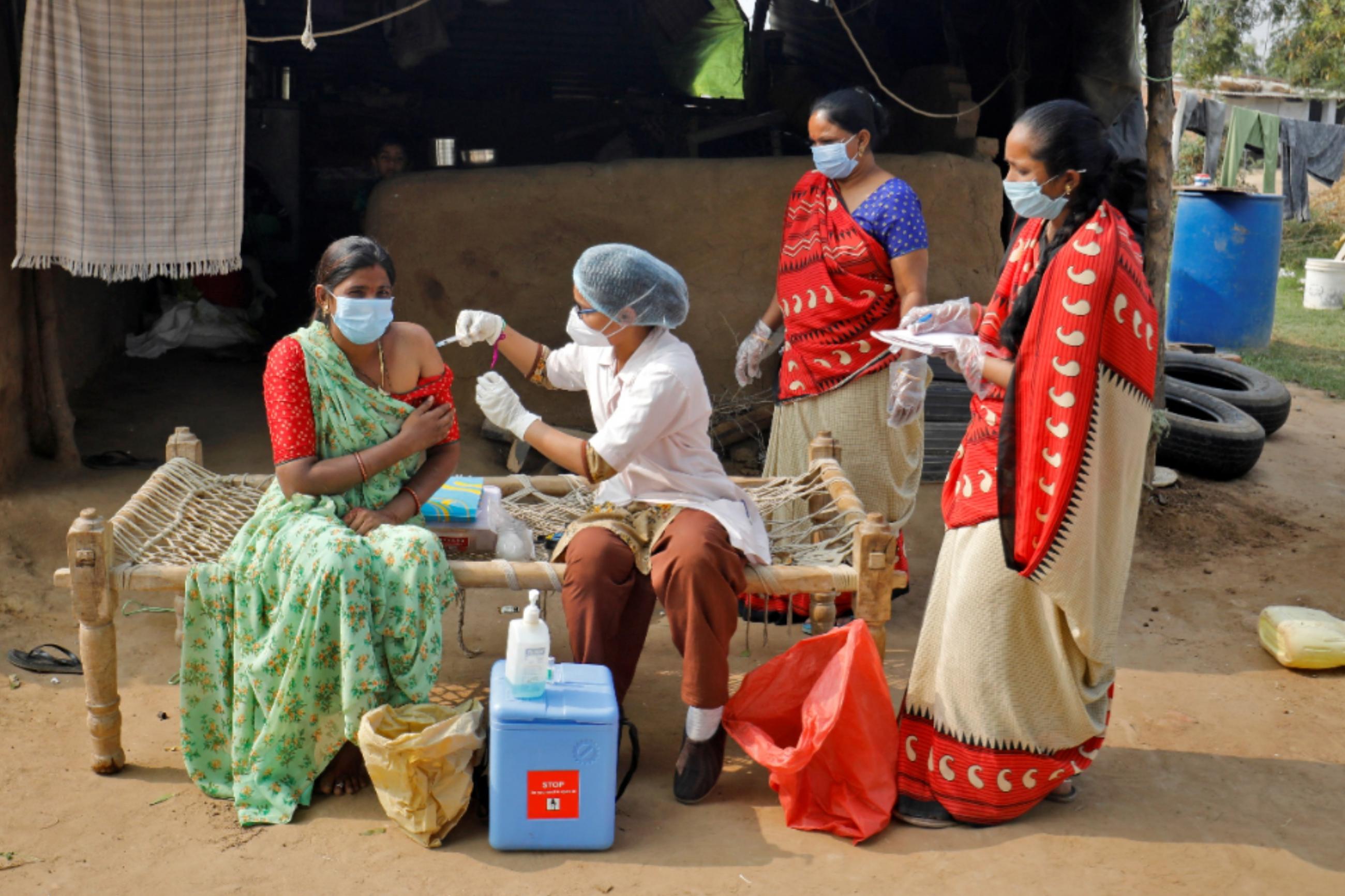 A woman in a green sari receives a dose of a COVID-19 vaccine manufactured by Serum Institute of India, outside her house during a door-to-door vaccination drive on the outskirts of Ahmedabad, India, on December 15, 2021. 