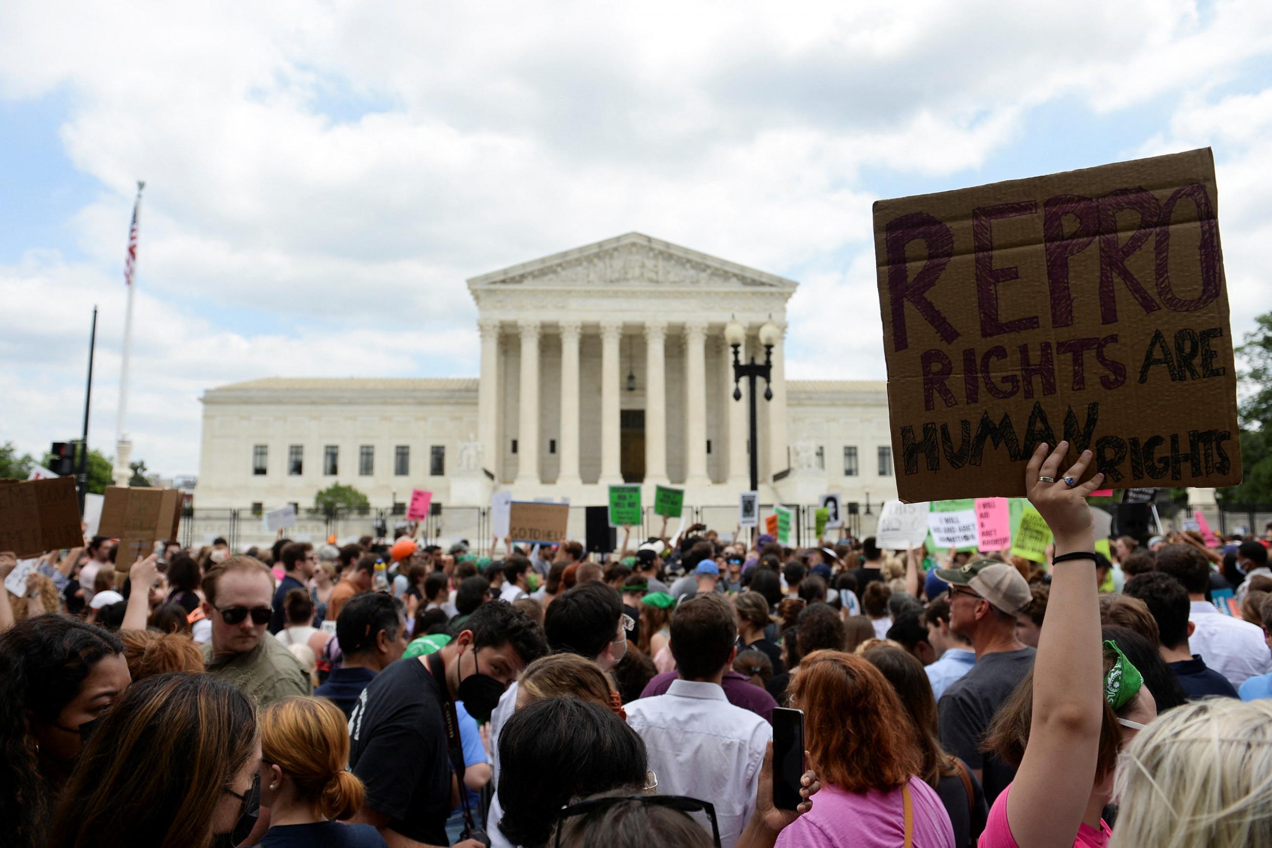 Abortion rights supporters holding pink and green signs face the white columns of the U.S. Supreme Court Building as they demonstrate against the Dobbs v Women's Health Organization ruling in Washington, U.S., June 24, 2022.