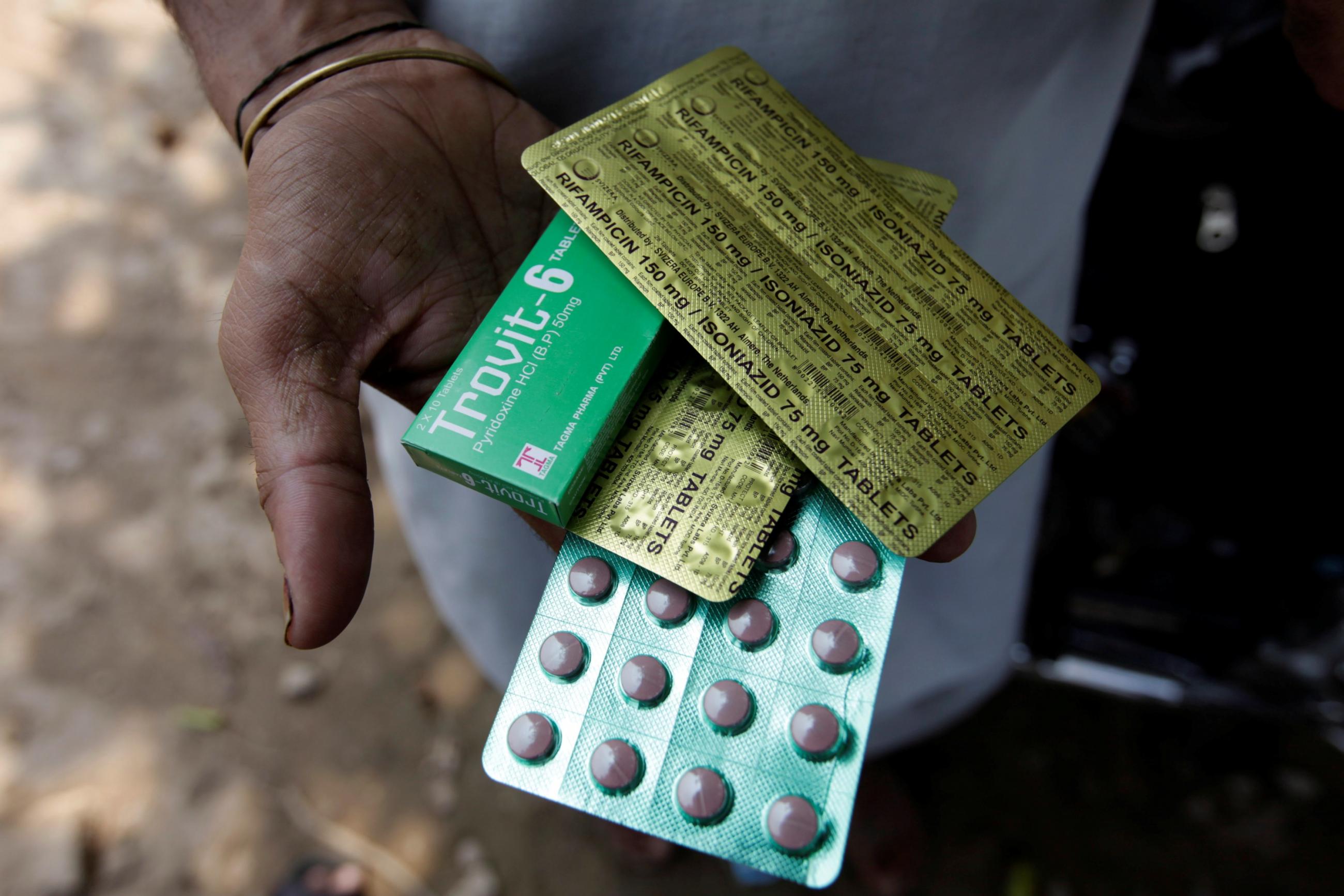 A tuberculosis patient holds his medicines received from the government's tuberculosis center in Rawalpindi, Pakistan July 11, 2016. The pink pills are sealed in rows of green packaging with gold foil on the back that gives the name and dosage of the drug.