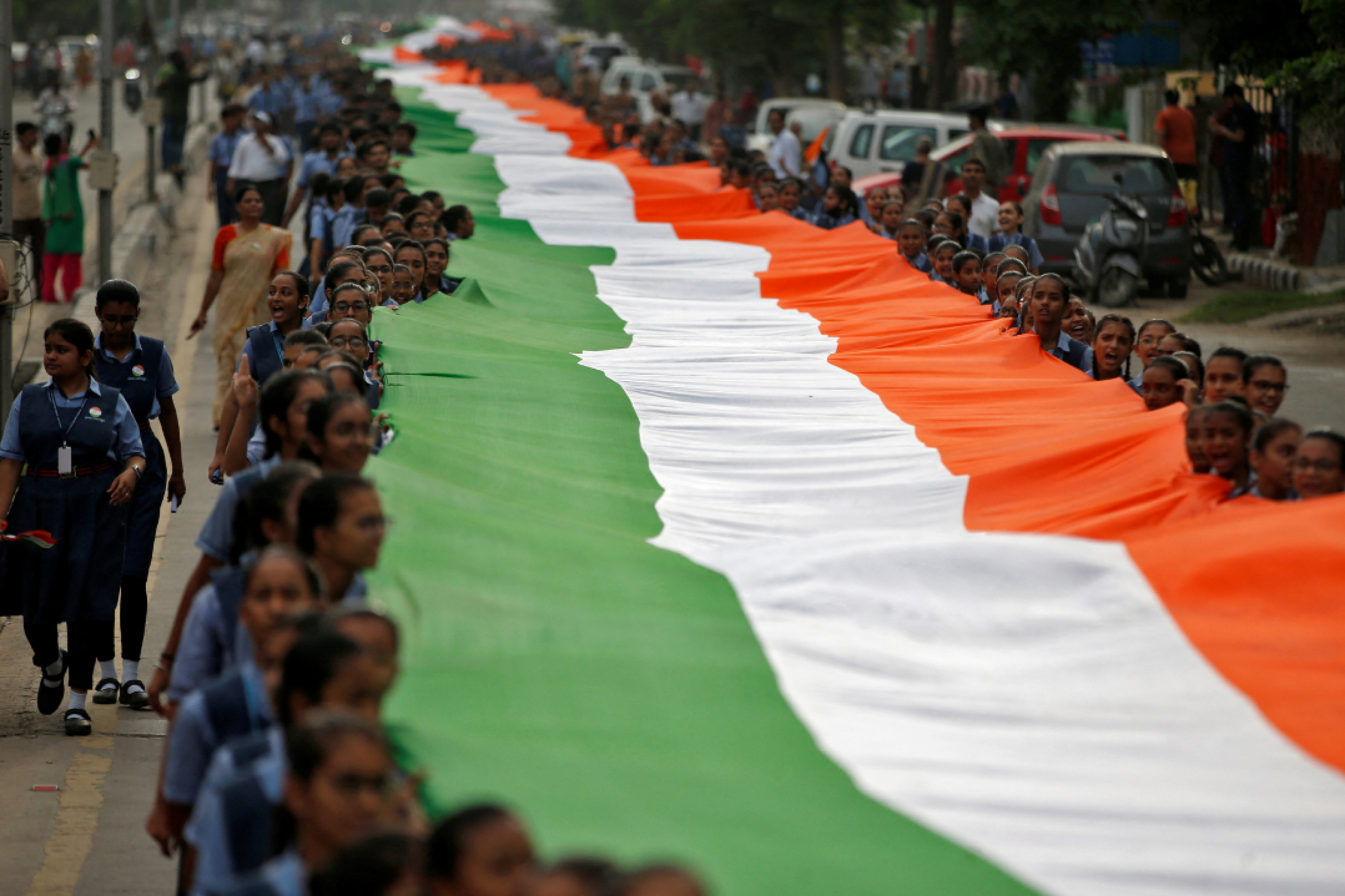 Students hold a giant Indian national flag with green, white and orange stripes, during celebrations commemorating 75 years of India's Independence, in Ahmedabad, India, August 8, 2022. 