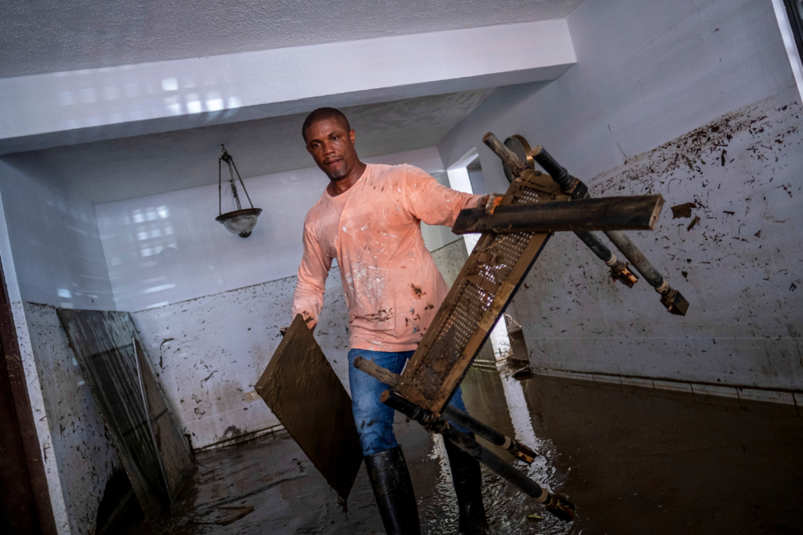 A man wades through knee-deep water in his home, carrying damaged furniture in the aftermath of Hurricane Fiona, in Toa Baja, Puerto Rico, on September 20, 2022. REUTERS/Ricardo Arduengo