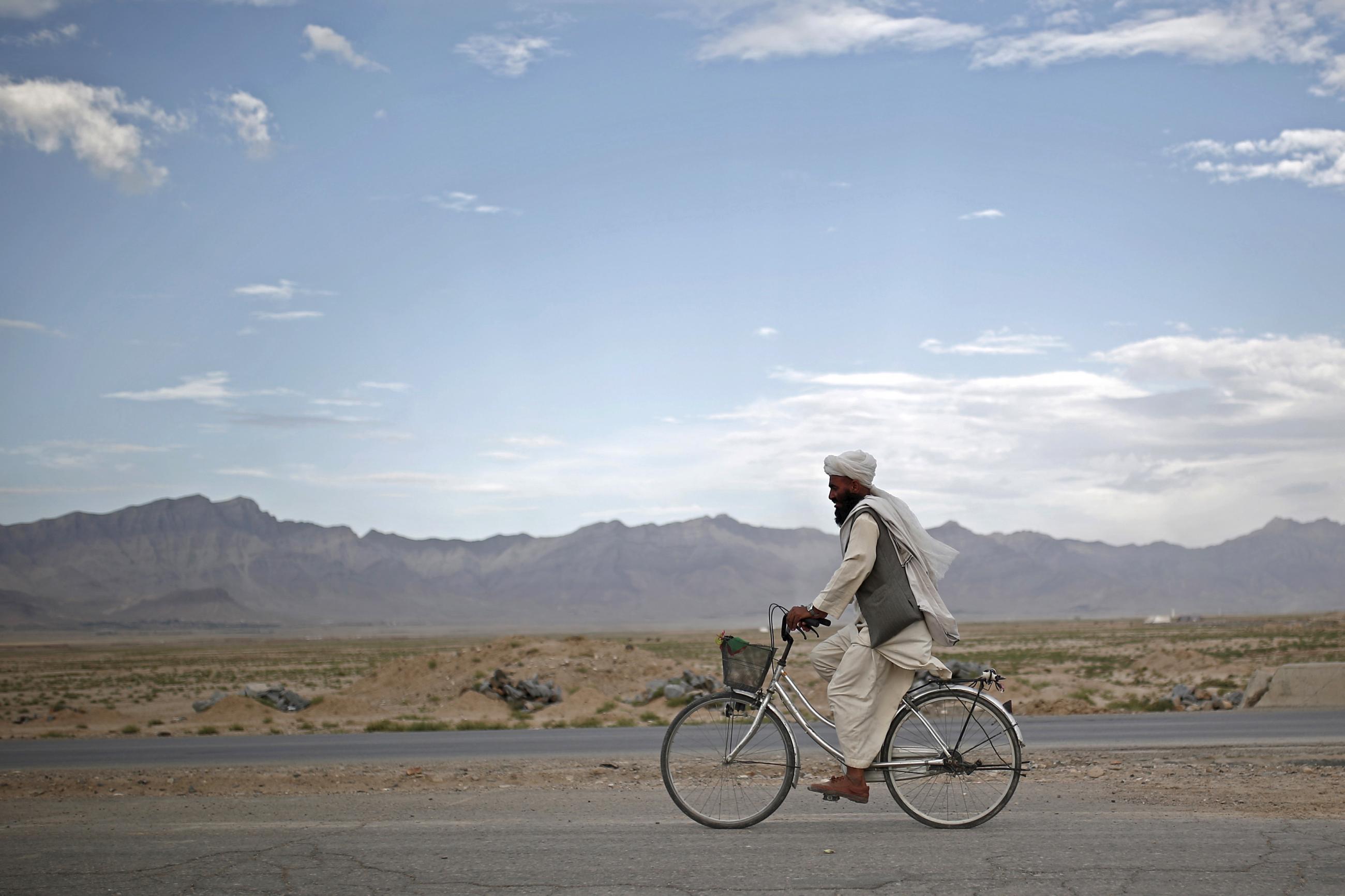 An Afghan man rides a bicycle on the outskirts of Kabul, Afghanistan, on July 30, 2015.