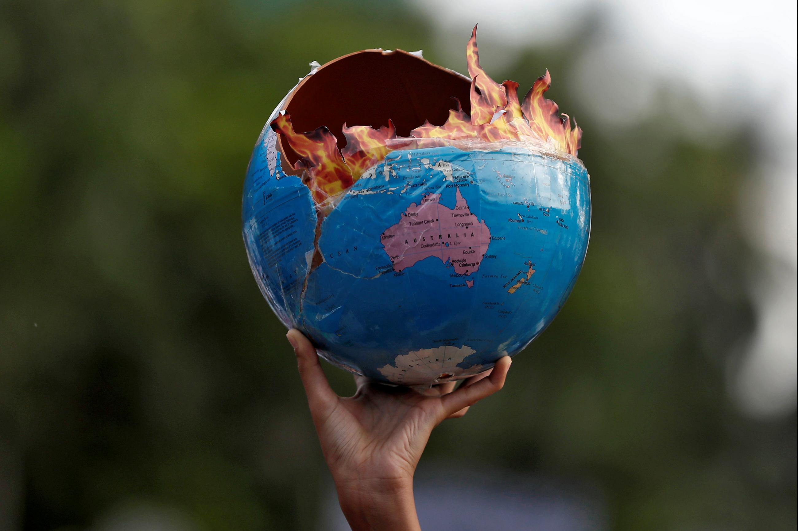 A protestor participating in a "Fridays for Future" march calling for urgent measures to combat climate change holds a globe designed to look like it is on fire, in Mumbai, India, on September 27, 2019. 