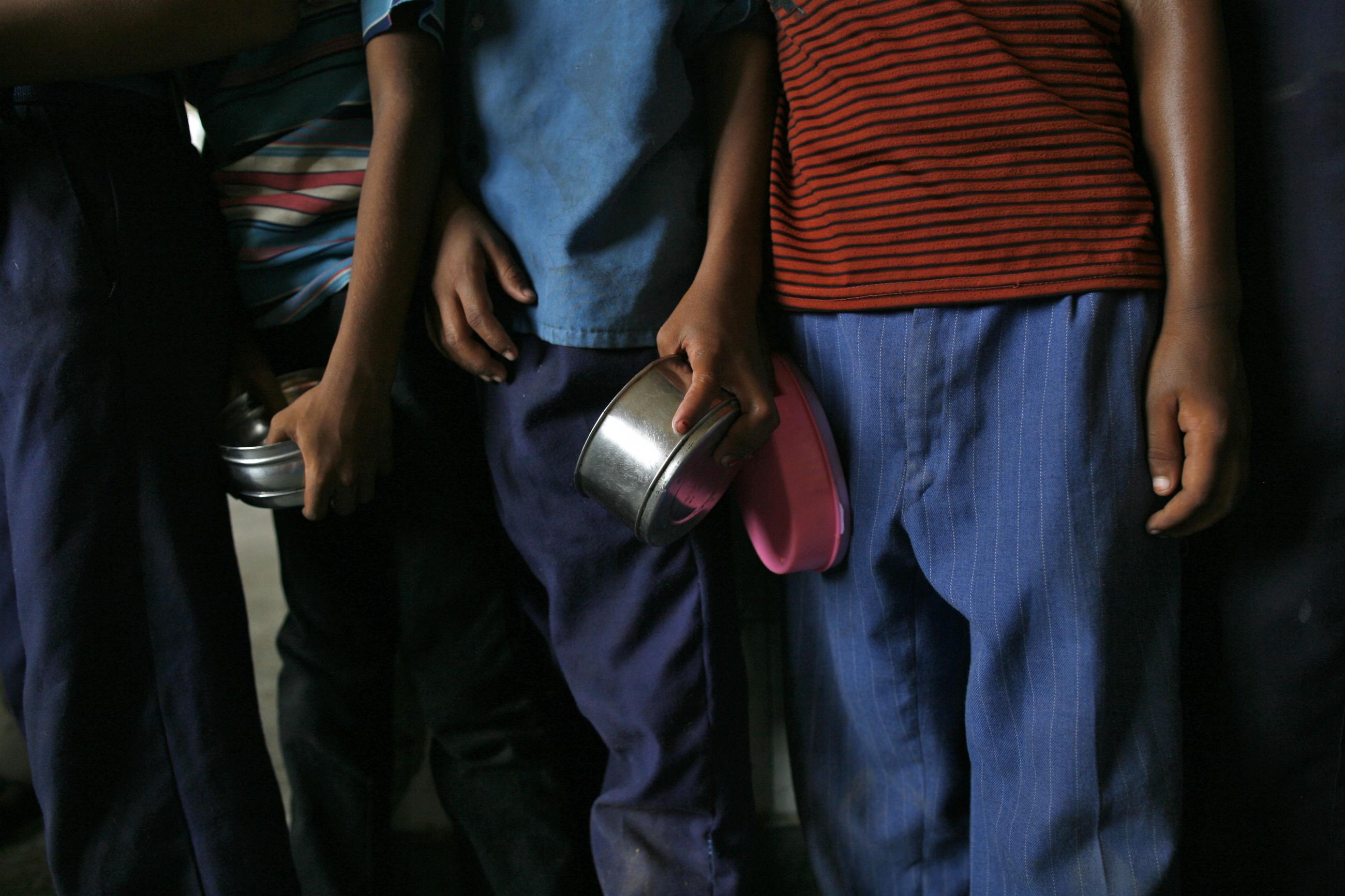 The arms of school boys are seen carrying their tiffin boxes as they wait to receive their free mid-day meal, distributed by a government-run primary school, in New Delhi July 19, 2013. 