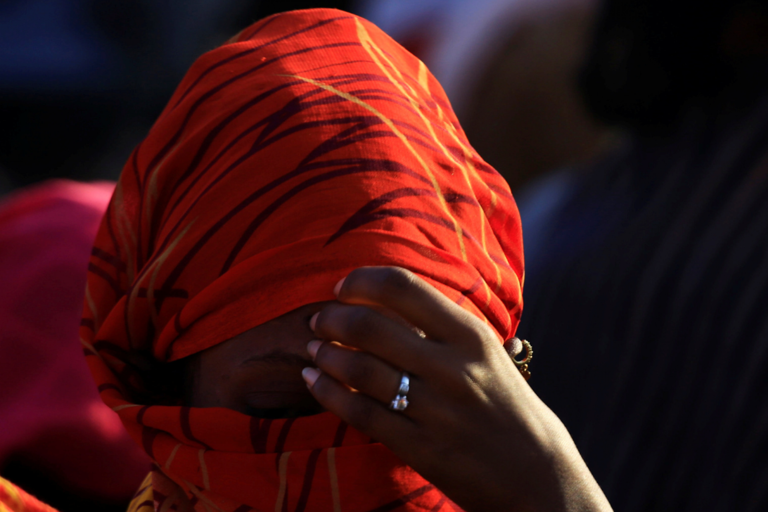 A close-up photo of an Ethiopian woman wearing a read head scarf with her hand held to her forehead. She fled the ongoing fighting in Tigray, in Hamdayet village near the Sudan-Ethiopia border, in Kassala State, Sudan, on November 22, 2020. 