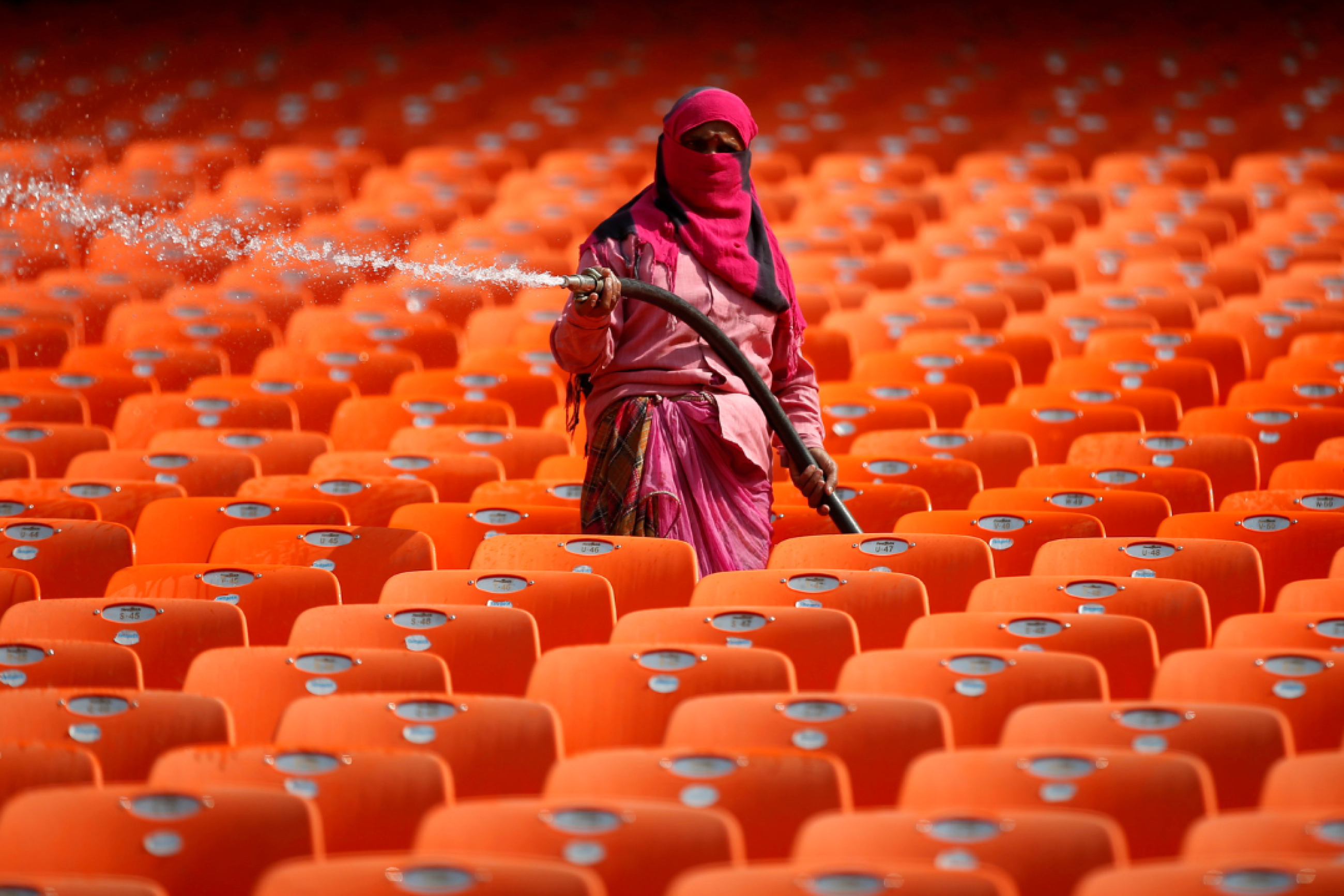 A worker hoses down bright orange seats in the stands at Sardar Patel Gujarat Stadium, during the COVID-19 pandemic, in Ahmedabad India, on February 17, 2021. 