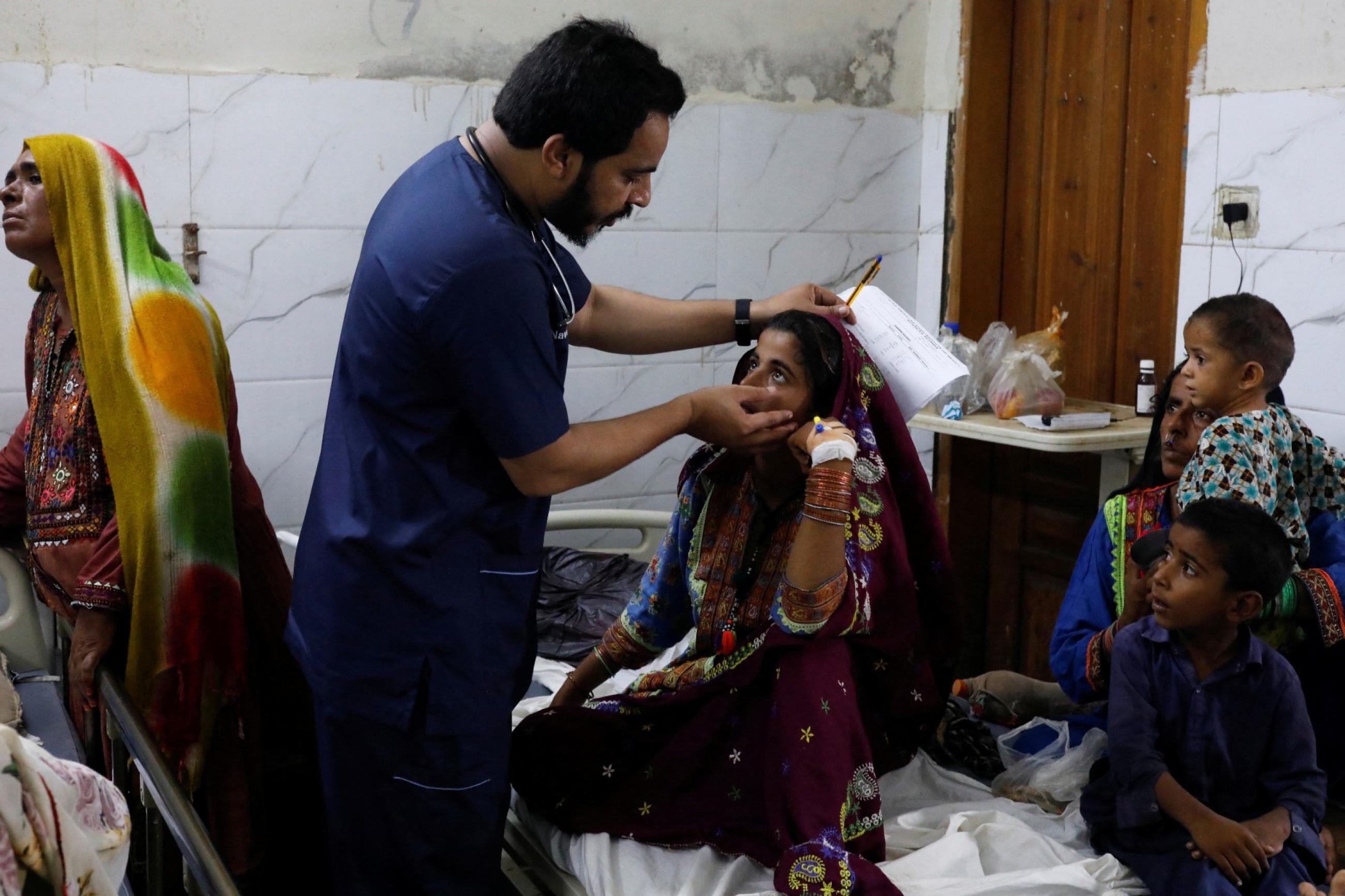 Naveed Ahmed, a doctor, gives medical assistance to Hameeda, who is suffering from malaria, at Sayed Abdullah Shah Institute of Medical Sciences in Sehwan, Pakistan, on September 29, 2022.