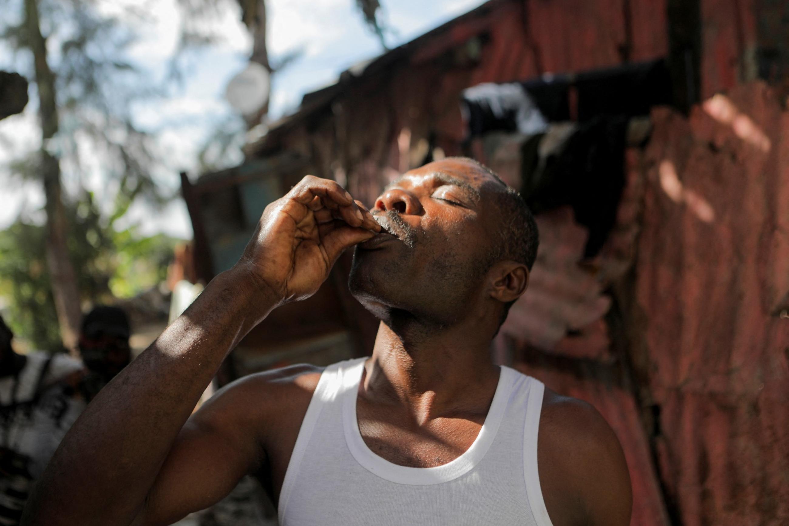 a man wearing a white tank top self-administers an oral cholera vaccine