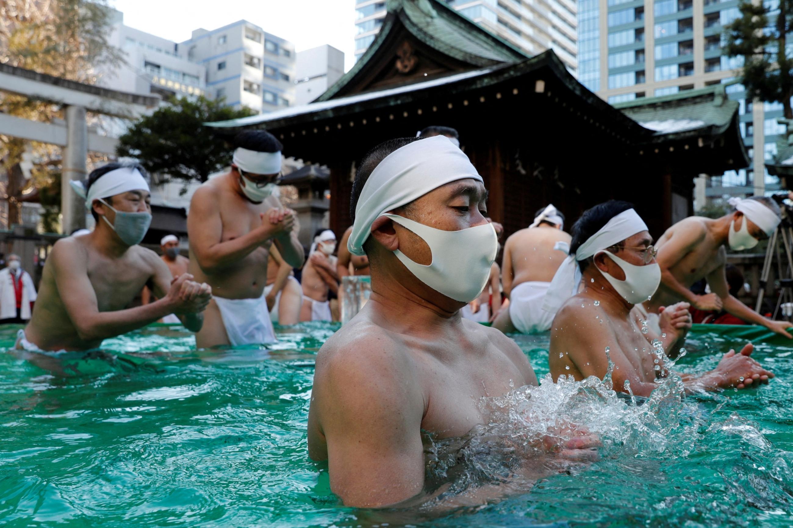 Participants wearing protective face masks amid the coronavirus disease (COVID-19) outbreak, pray as they take an ice-cold bath during a ceremony to purify their souls and to wish for overcoming the pandemic at the Teppozu Inari shrine in Tokyo, Japan, January 9, 2022.