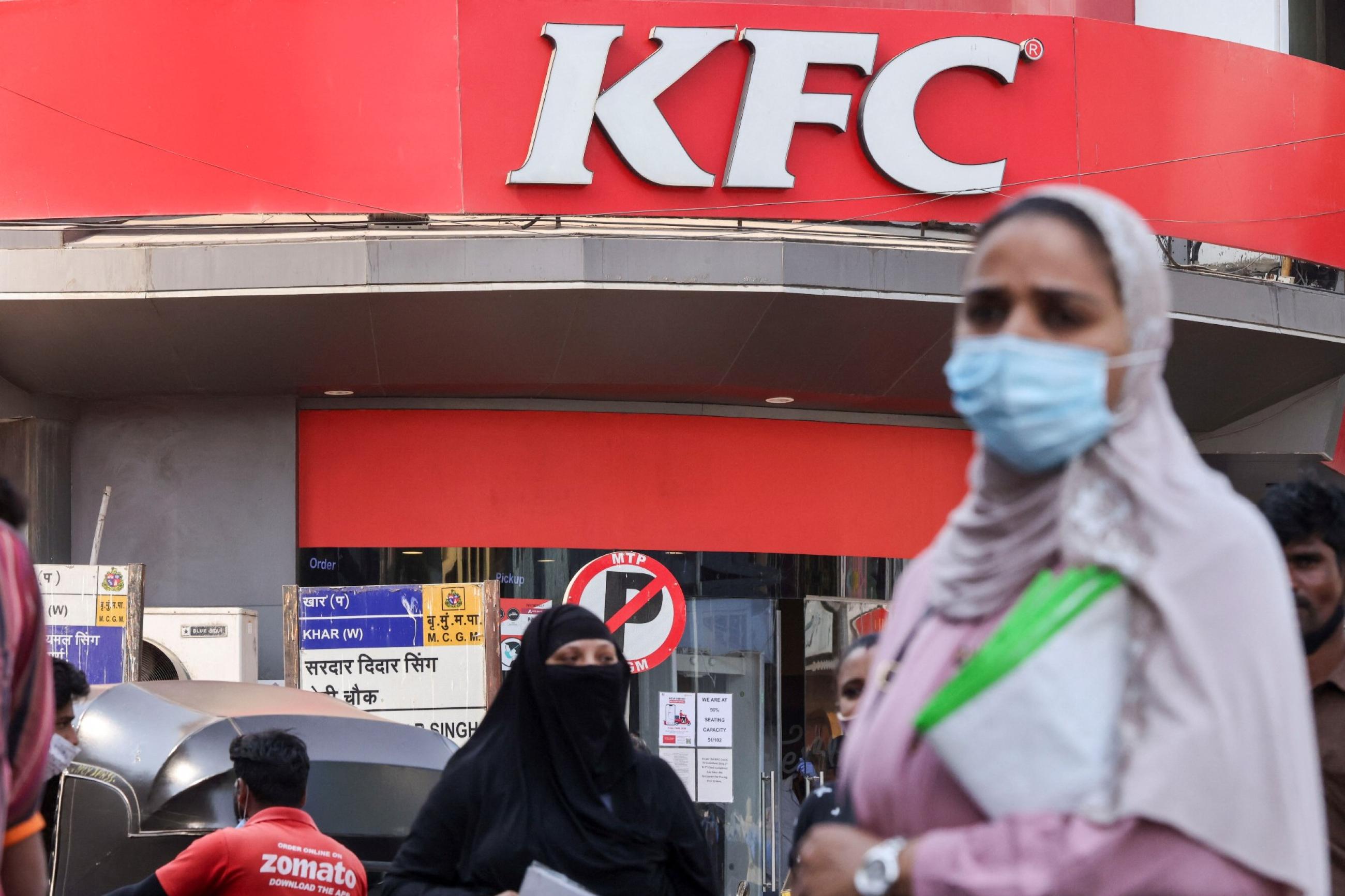 a woman stands in front of a kfc