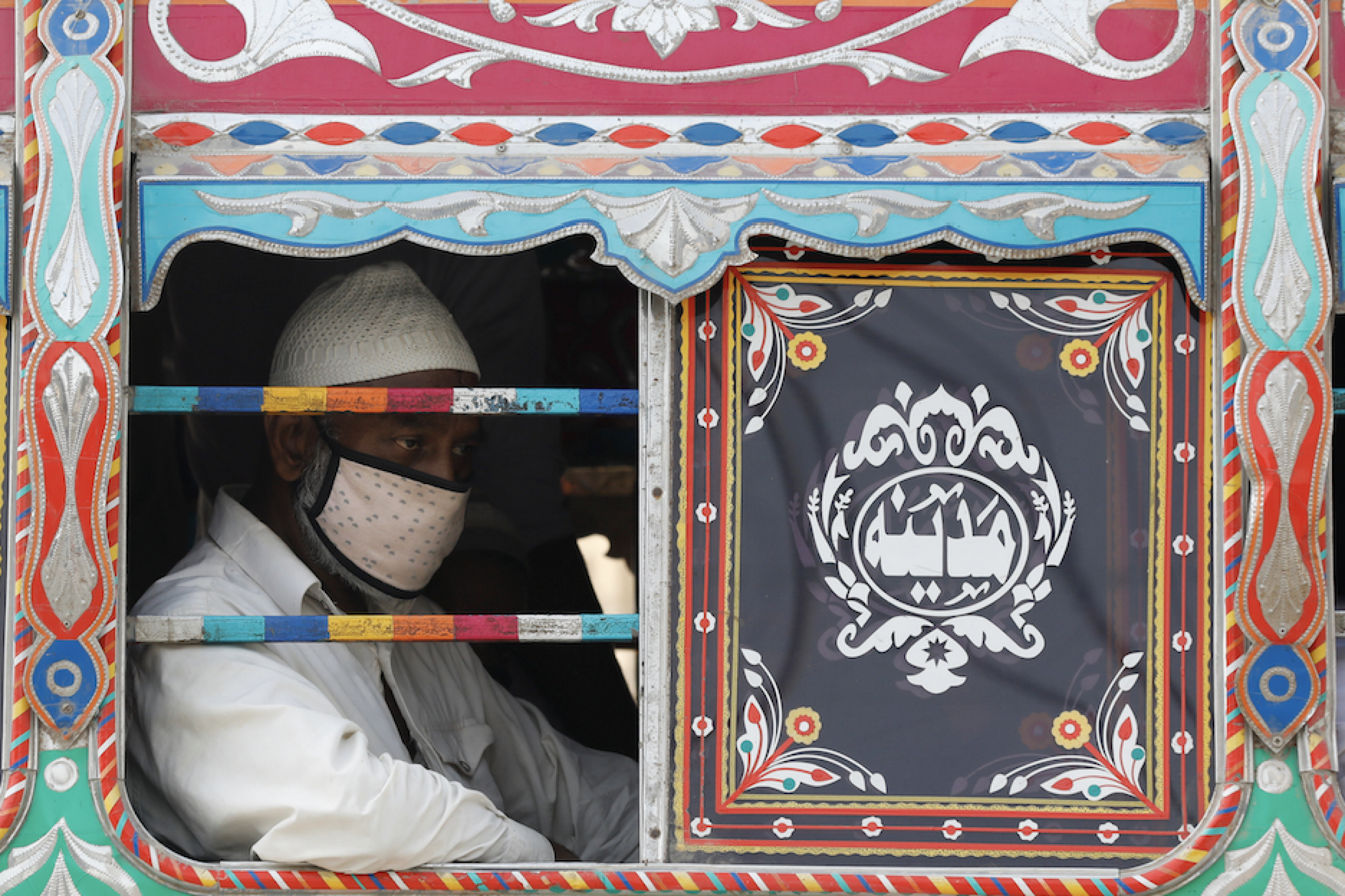 A passenger wearing a protective face mask is seen from the window of a bus, after the provincial government started easing the lockdown restrictions and allowed to resume city public transport in Sindh, as the outbreak of the coronavirus disease (COVID-19) continues, in Karachi, Pakistan June 3, 2020. REUTERS/Akhtar Soomro
