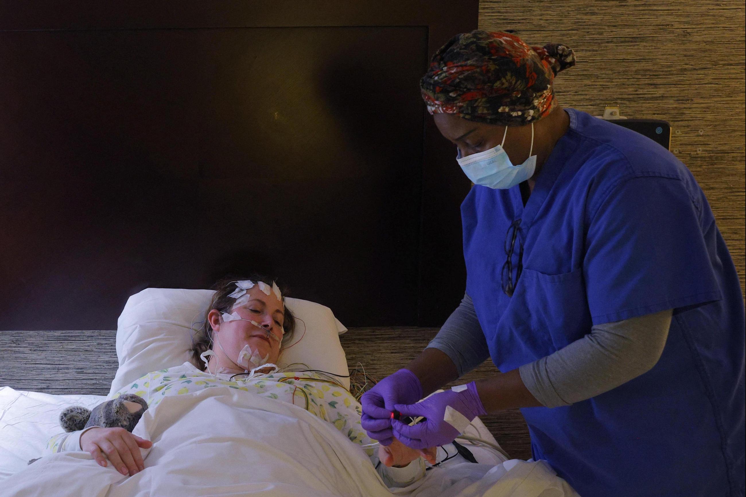Polysonographer Marie Derolus prepares Ghenya Grondin, who first was sick with COVID-19 in March 2020 and has had long COVID ever since, for a sleep study in Boston, Massachusetts, U.S., December 12, 