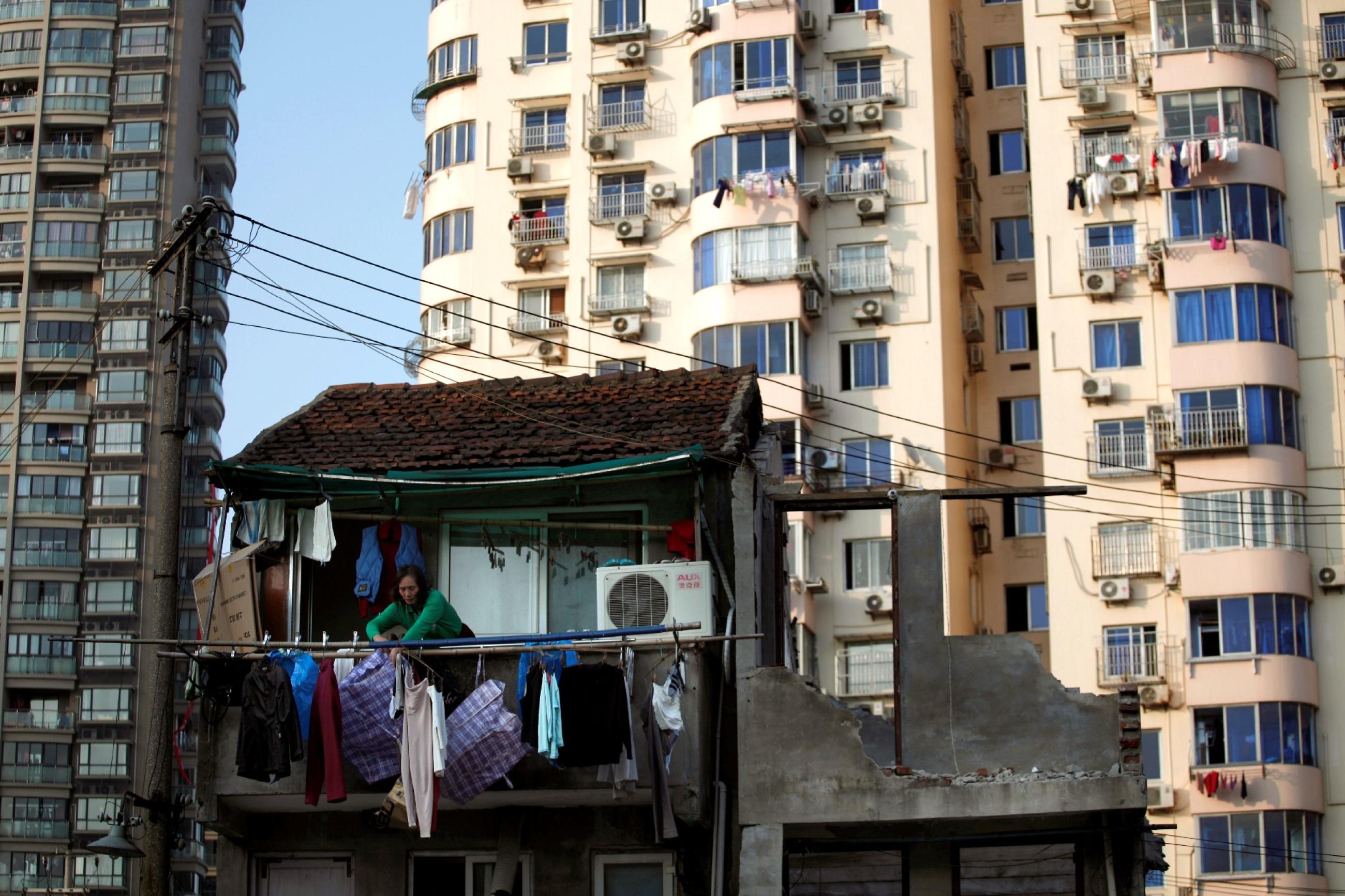 A woman stands at the balcony of her house which will be demolished to build new apartments in downtown Shanghai, China, on December 1, 2010. 