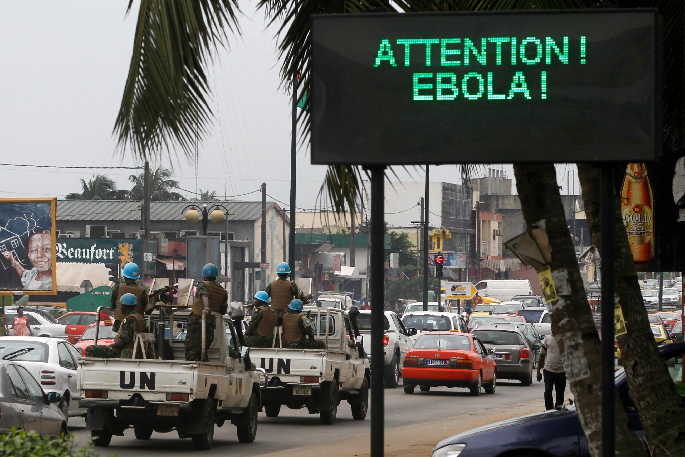 A U.N. convoy of soldiers passes a screen displaying a message on Ebola on a street in Abidjan August 14, 2014. 