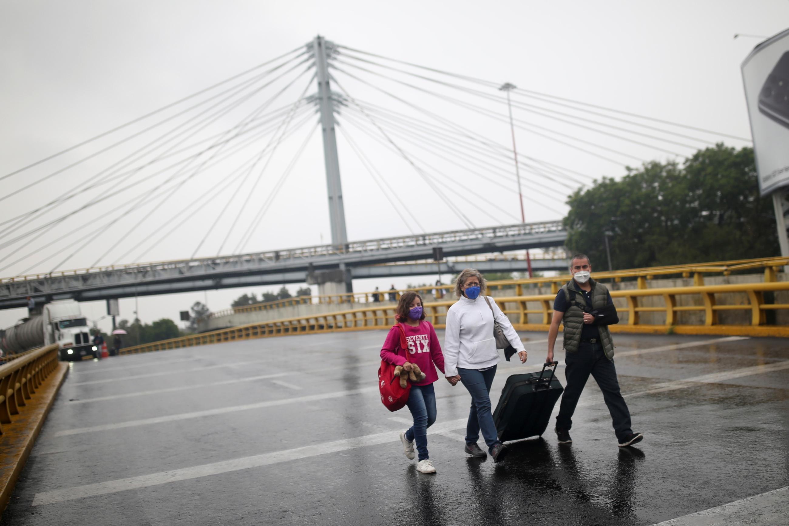 Three passengers walk down a street at Benito Juarez International Airport while parents of children with cancer block access in protest of the federal government due to cancer medication shortages.  
