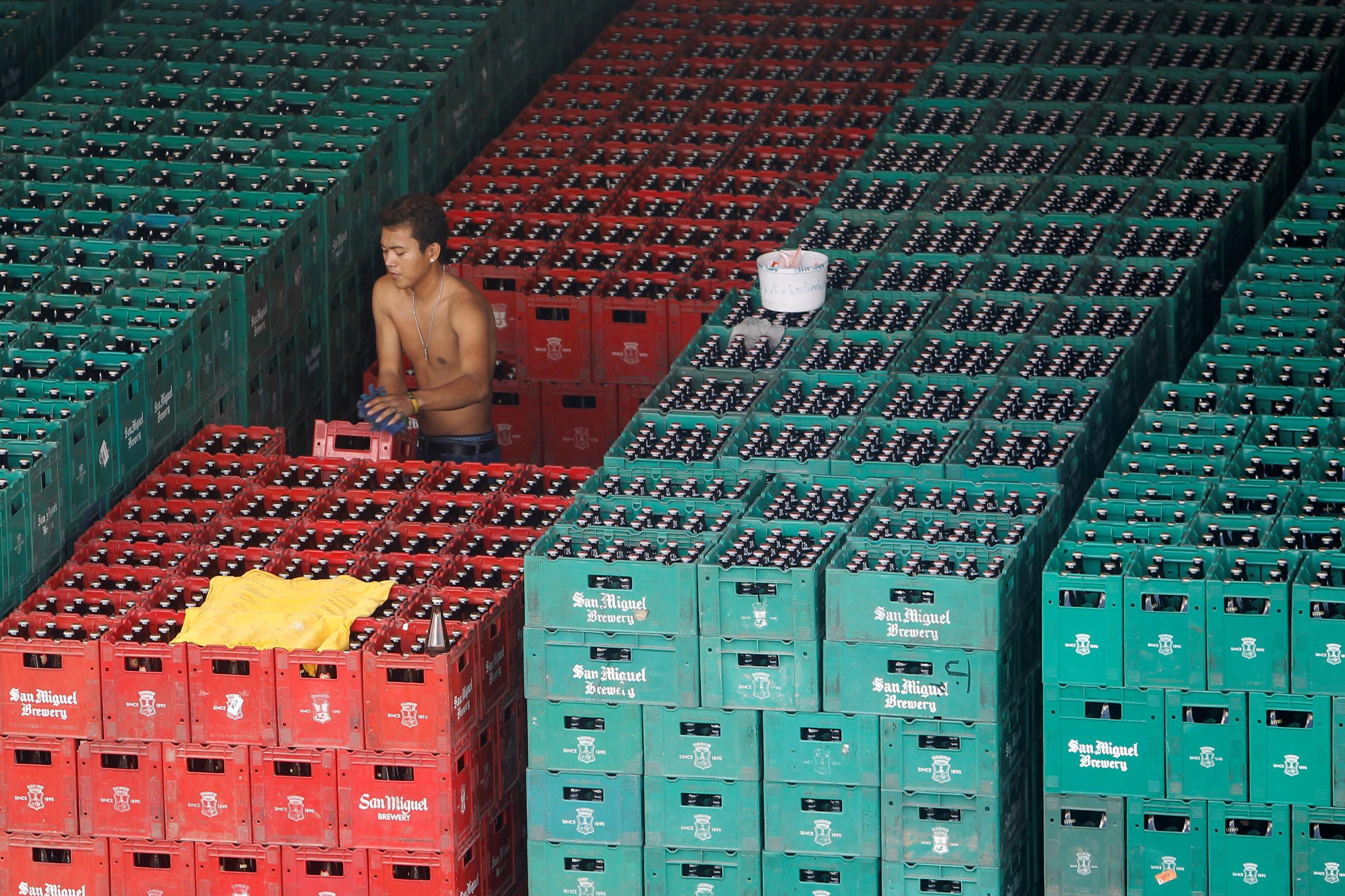 A worker arranges crates of beer before loading them onto a truck inside a San Miguel beer warehouse in Manila, November 14, 2012.