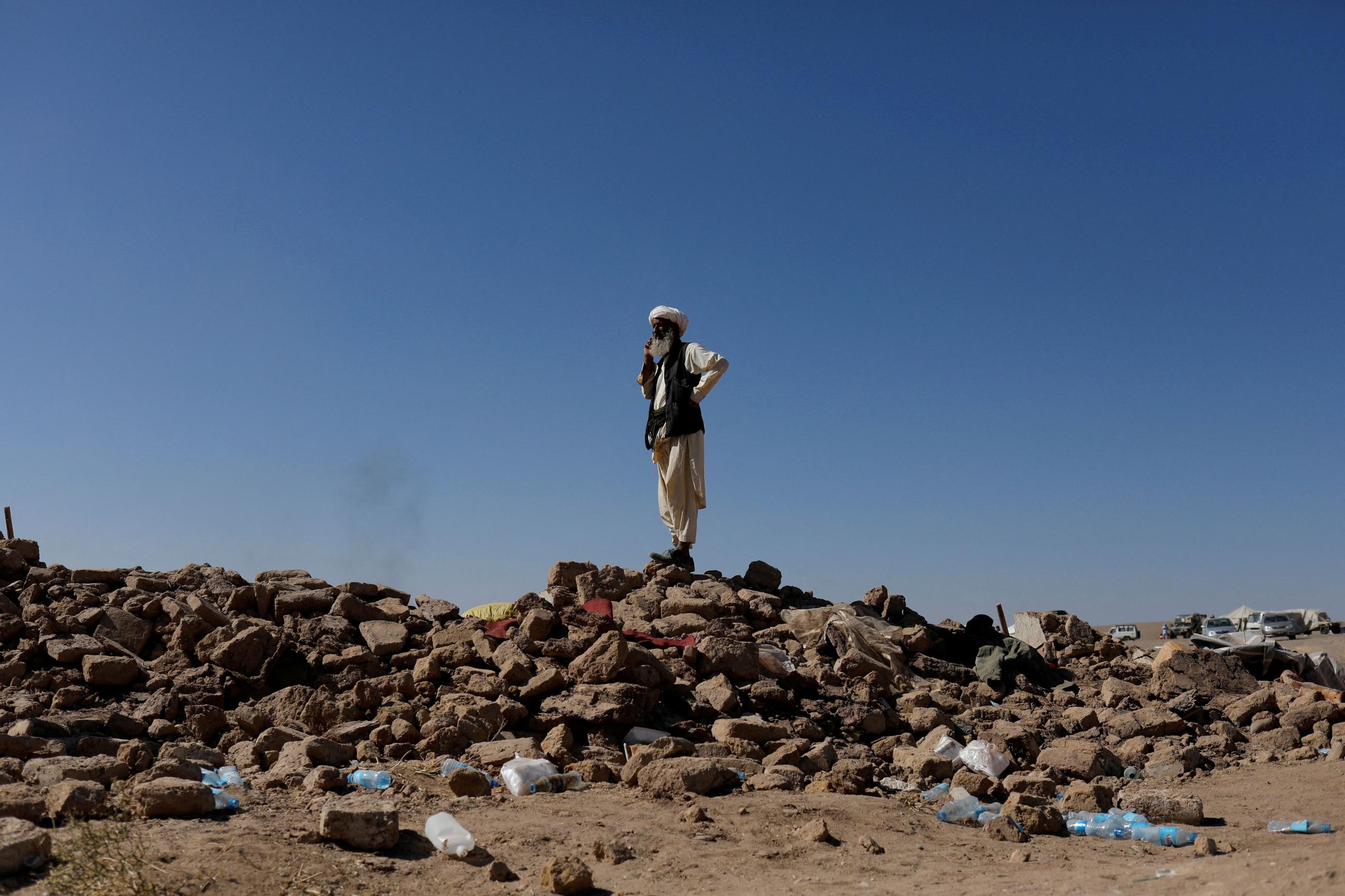 An Afghan man stands on the debris of damaged houses after the recent earthquake, in the district of Zinda Jan, in Herat, Afghanistan, October 9, 2023. 