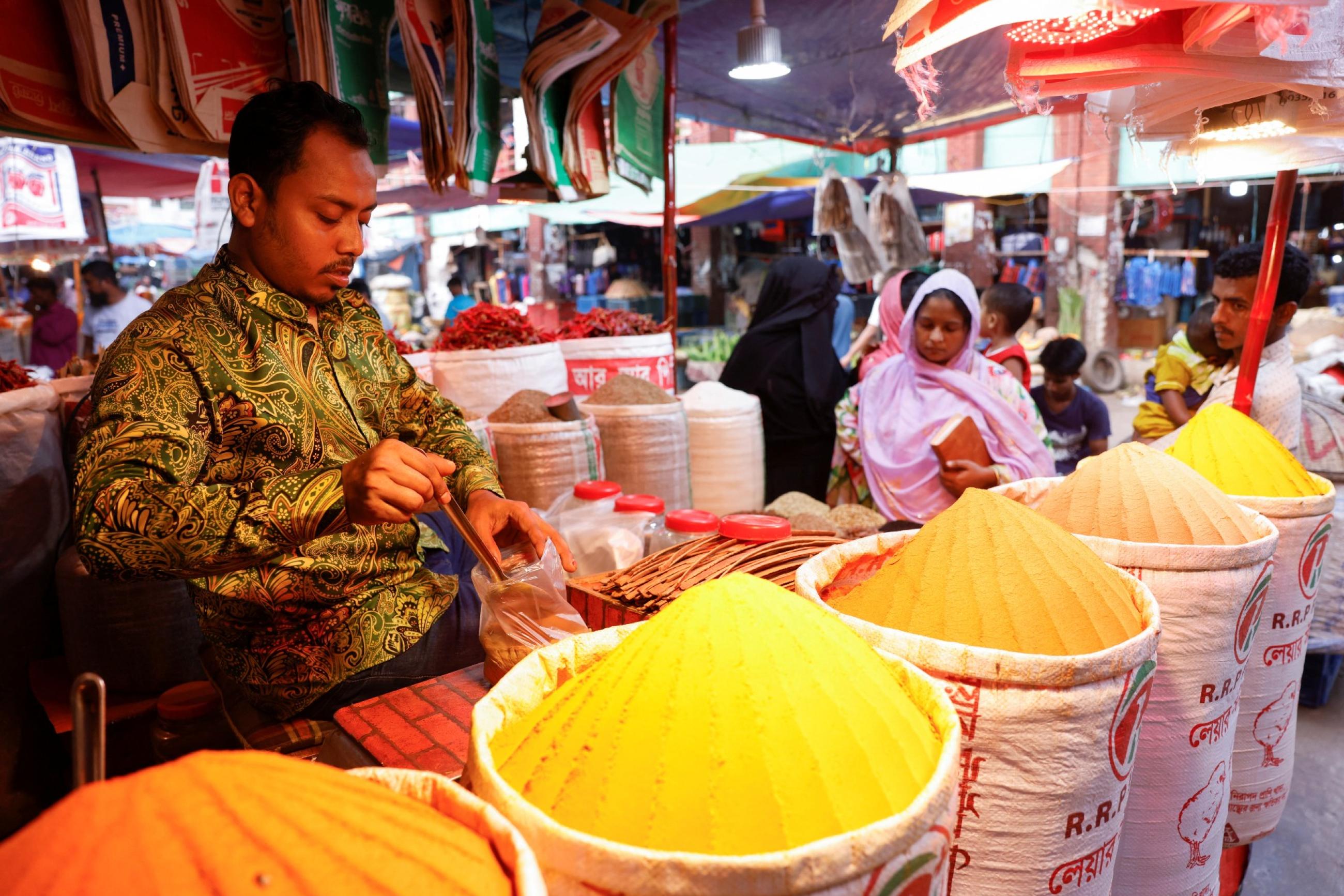 Man is seen in front of multiple piles of spices 