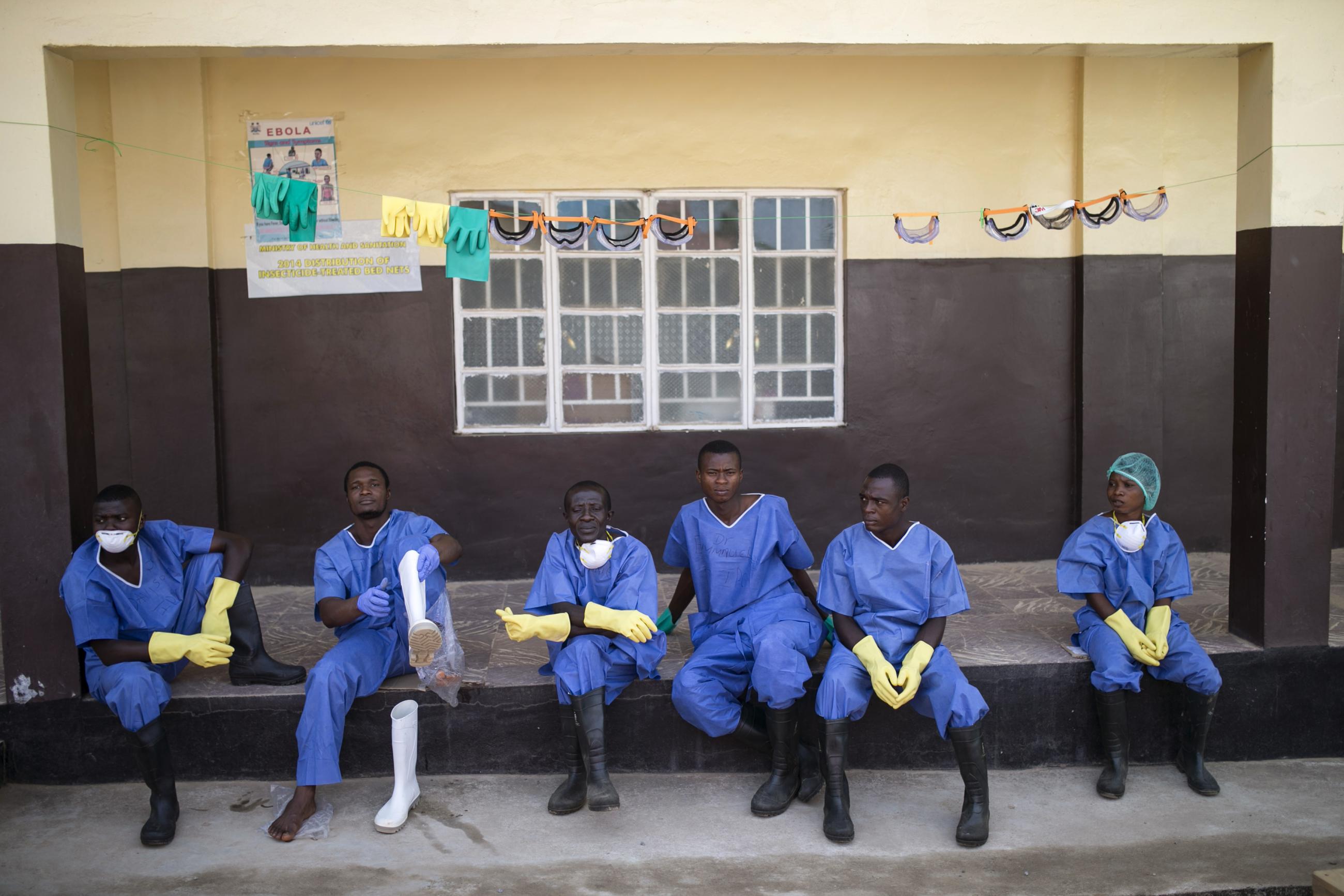 Health workers rest outside a quarantine zone at a Red Cross facility