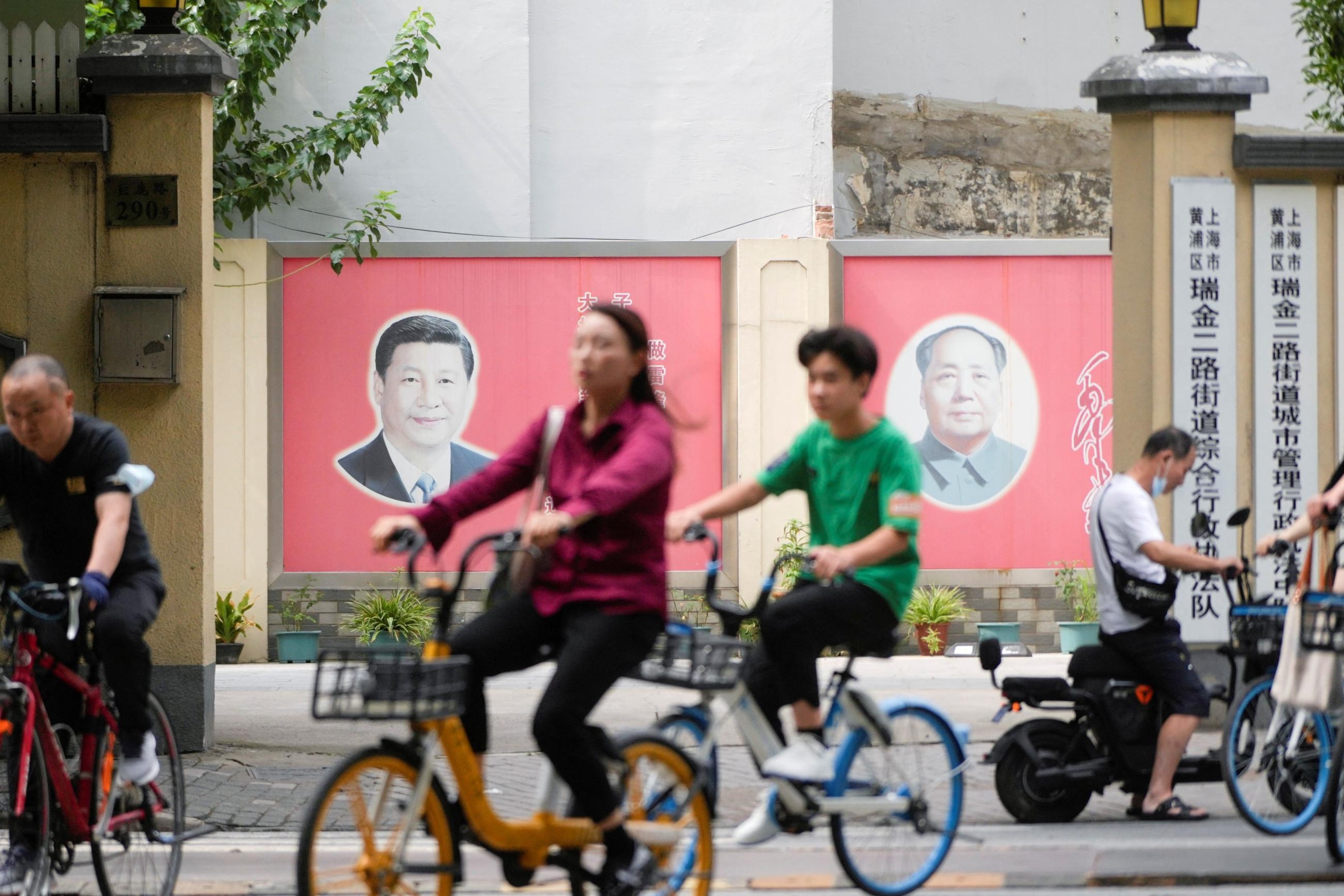 People pass by portraits of Chinese President Xi Jinping and late Chinese chairman Mao Zedong.