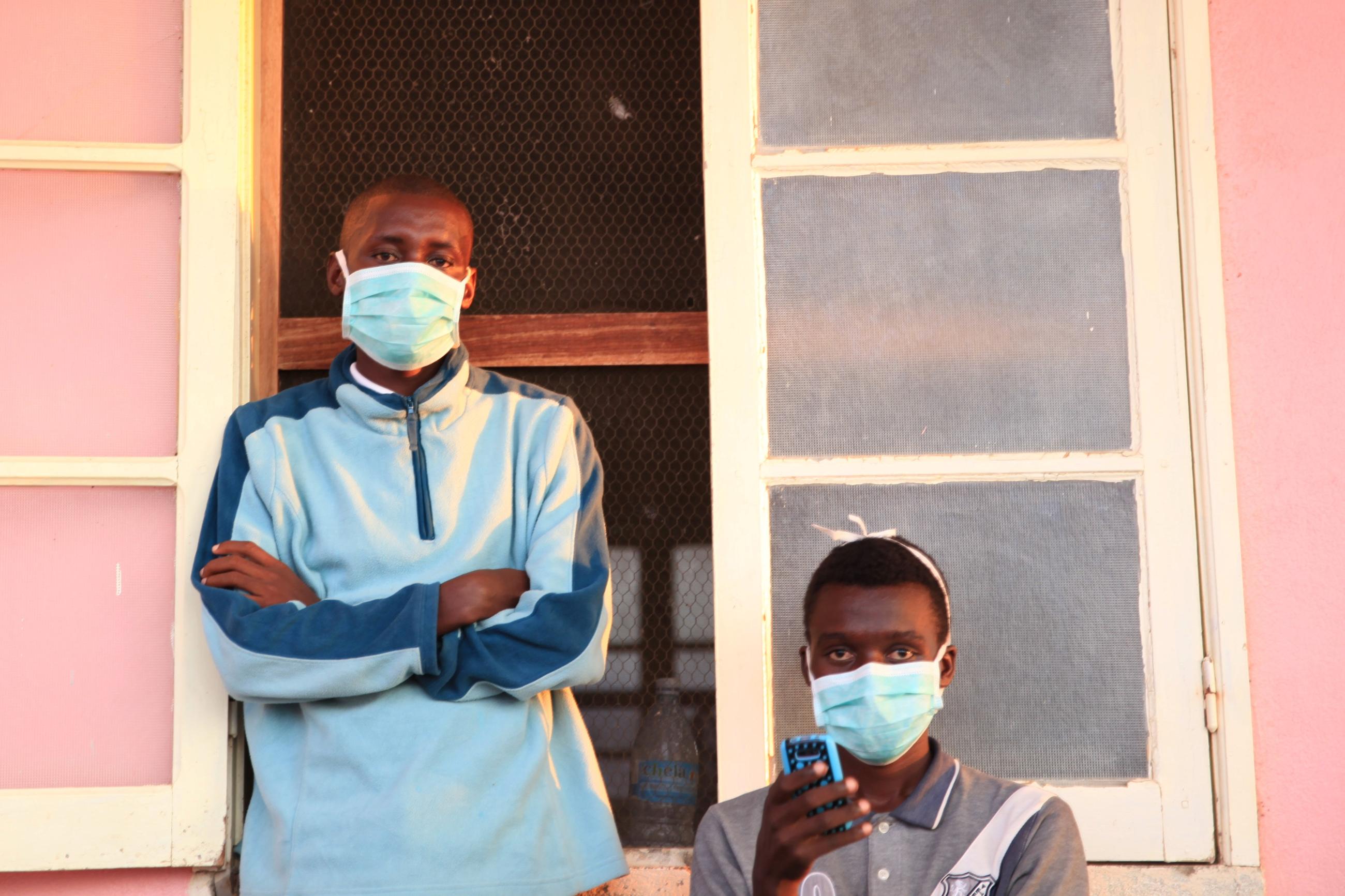 Tuberculosis patients, wearing masks to stop the spread of the disease, stand outside their ward at Chiulo Hospital.