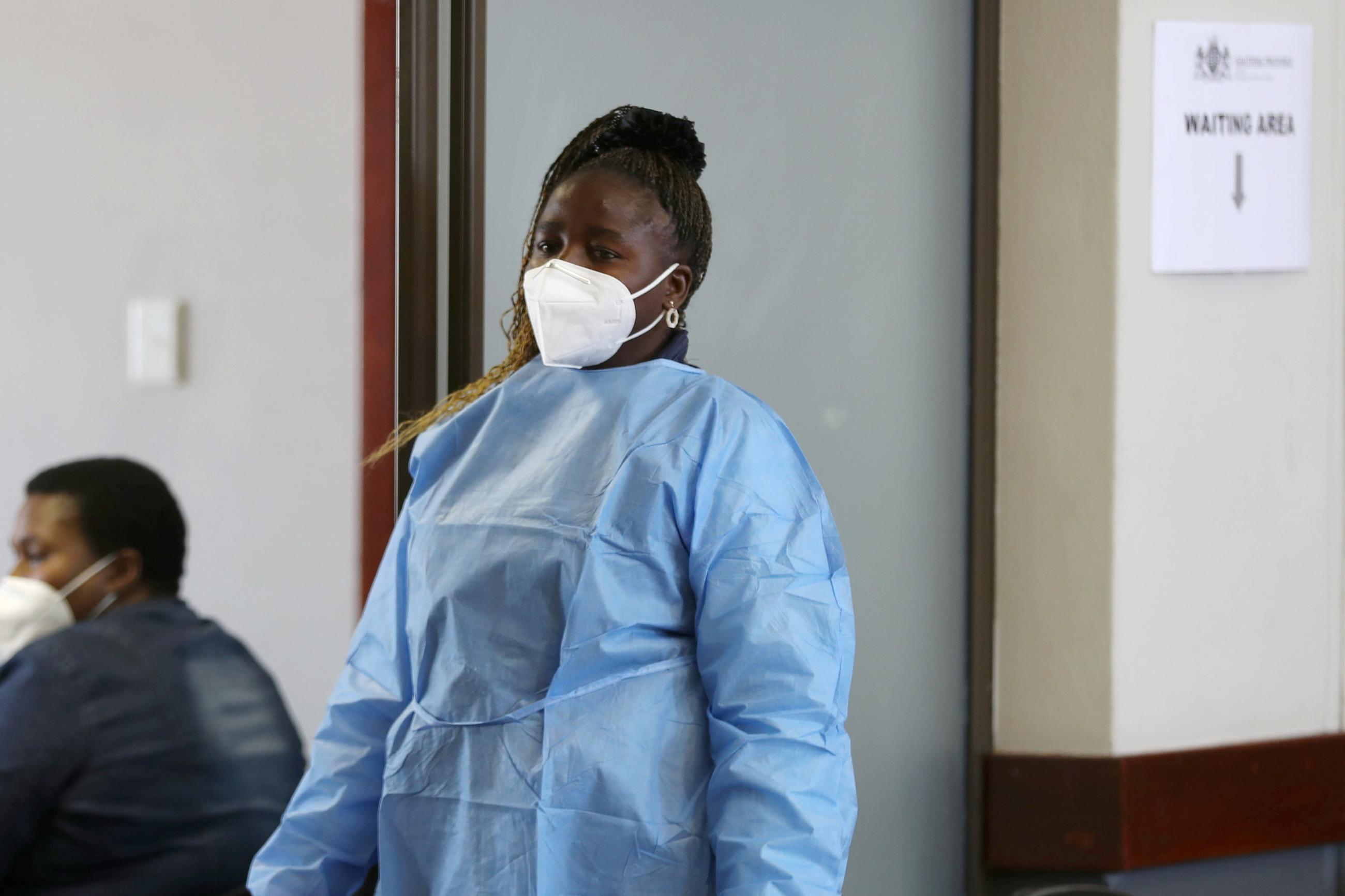 A health worker looks on as she waits to give a dose of a COVID vaccine.