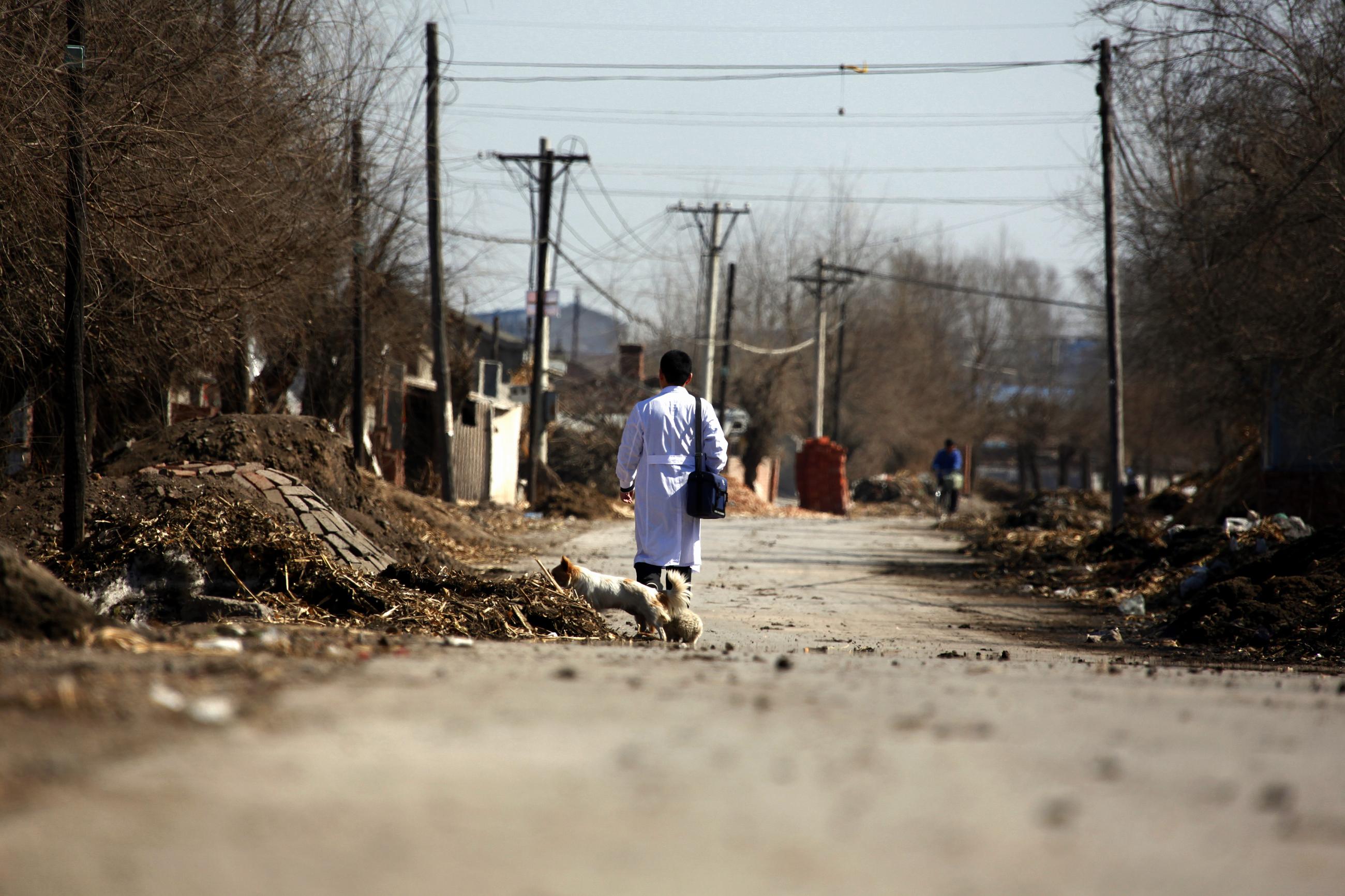 Doctor Li Tongqiang walks along a road through the village of Jianhua.